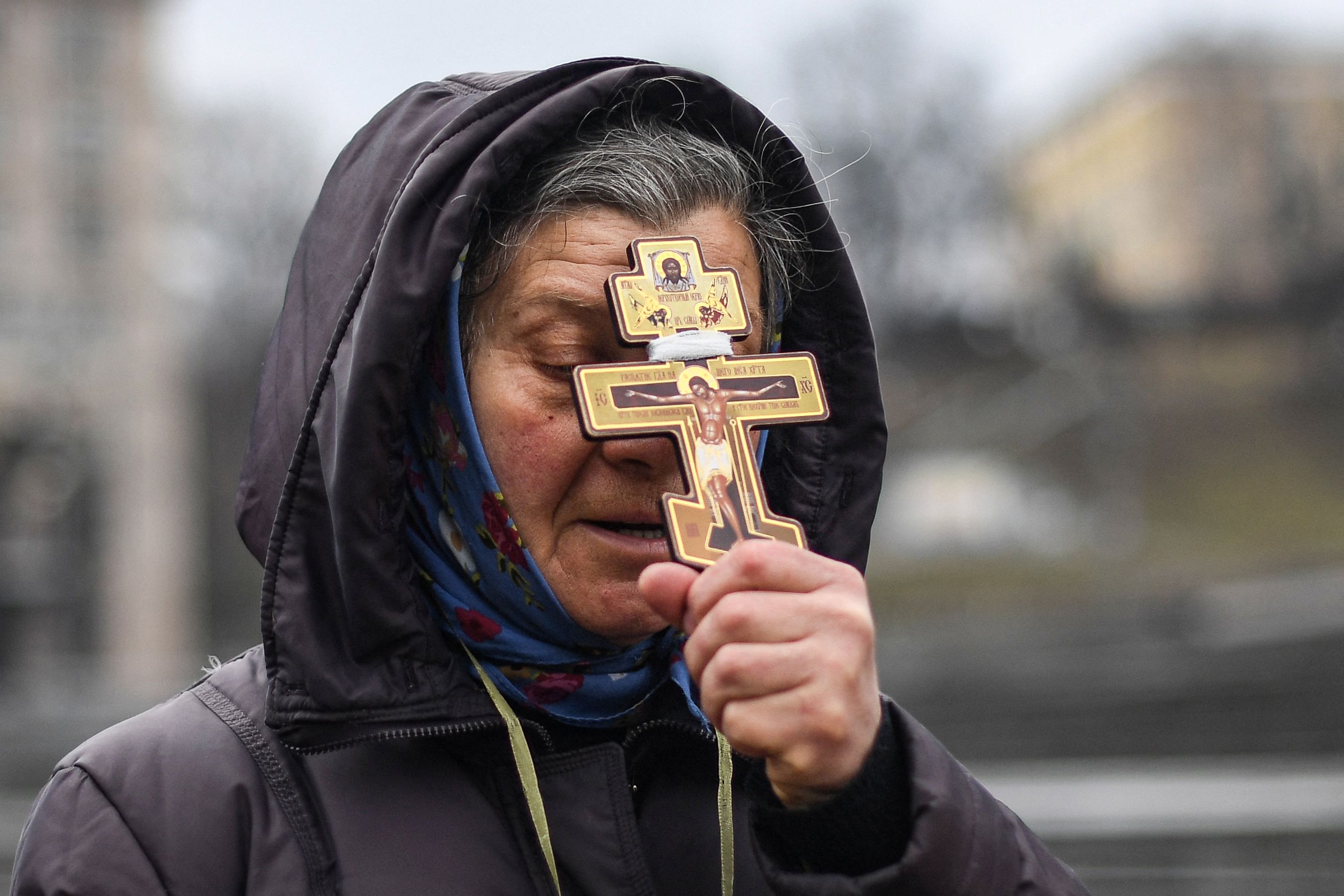 A religious woman holds a cross as she prays on Independence square in Kyiv in the morning of February 24.