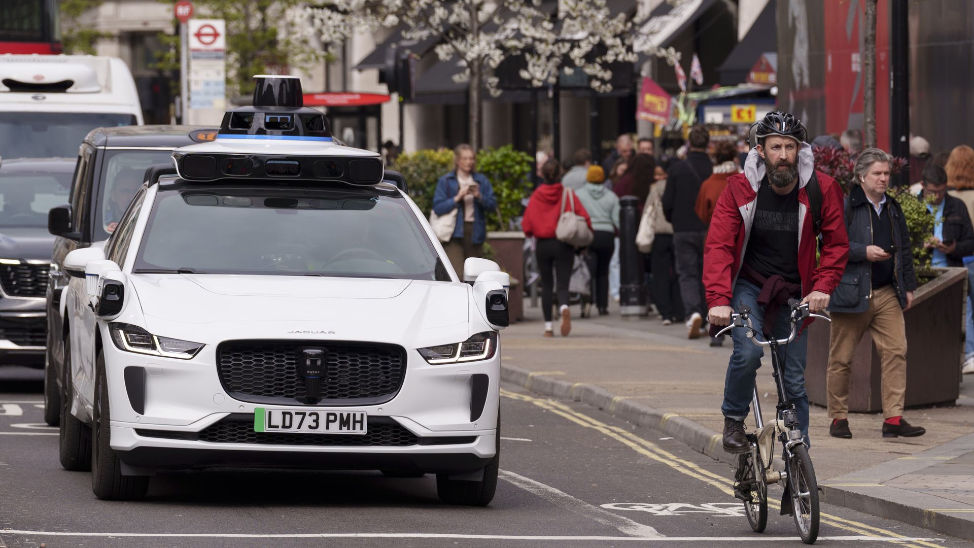 A cyclist rides past a Waymo self-driving Jaguar robotaxi at Oxford Circus in the West End, on 1st April 2026, in London, England.