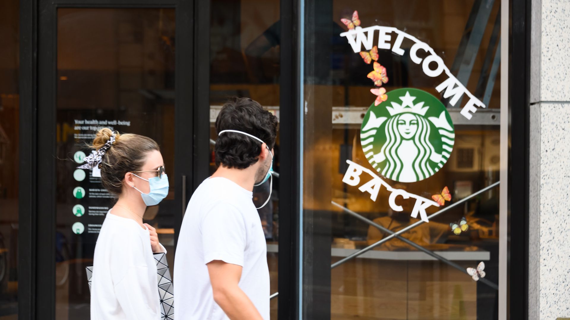 Two masked people walk past a Starbucks sign