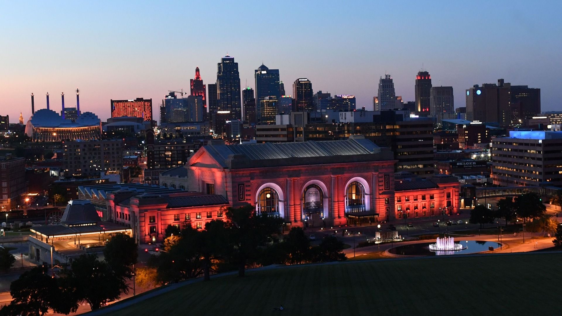 Photo of Kansas City skyline lit up orange and red at dusk.