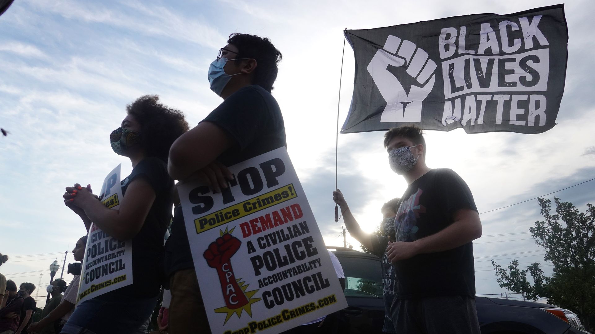 Photo of a person holding a Black Lives Matter flag at a protest outdoors