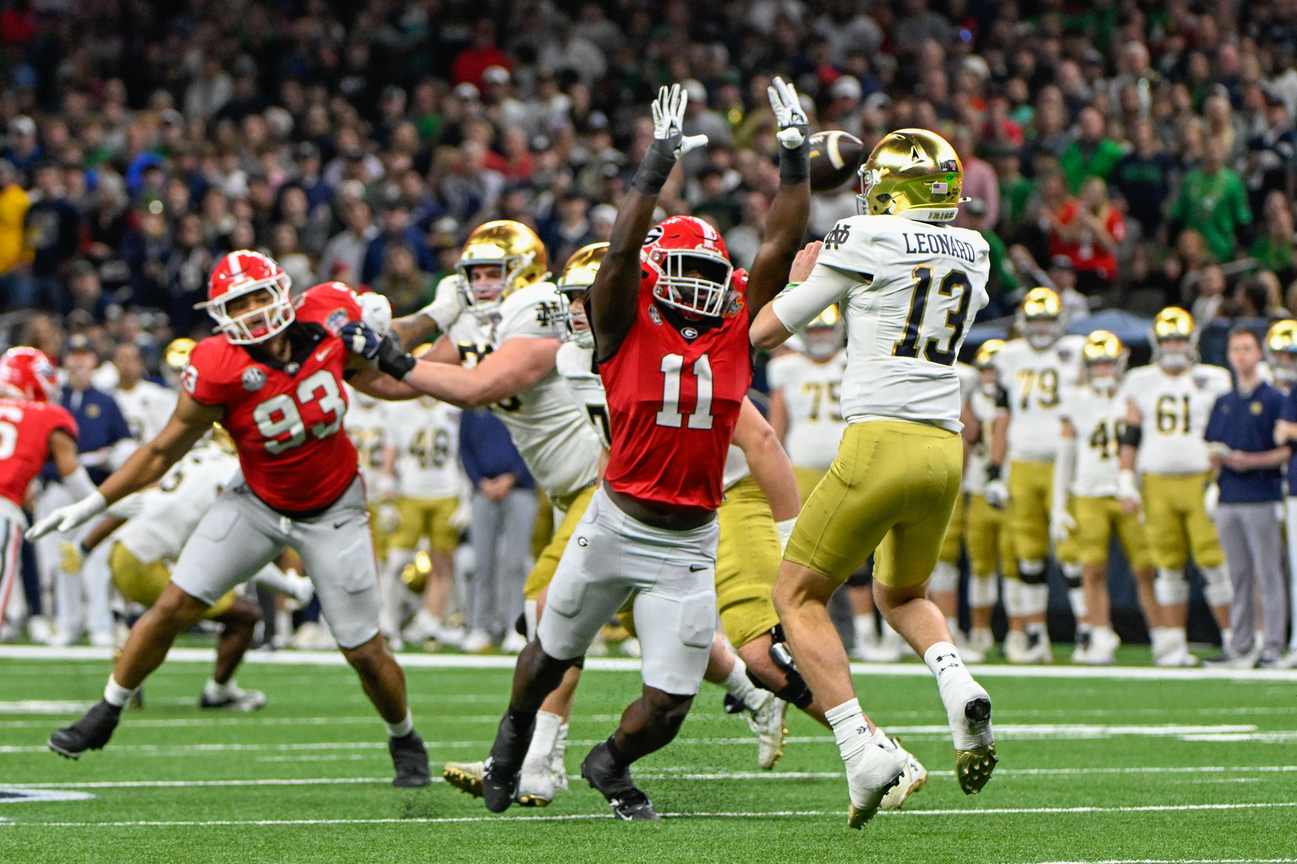 Photo of a football game where a player is trying to block a pass.