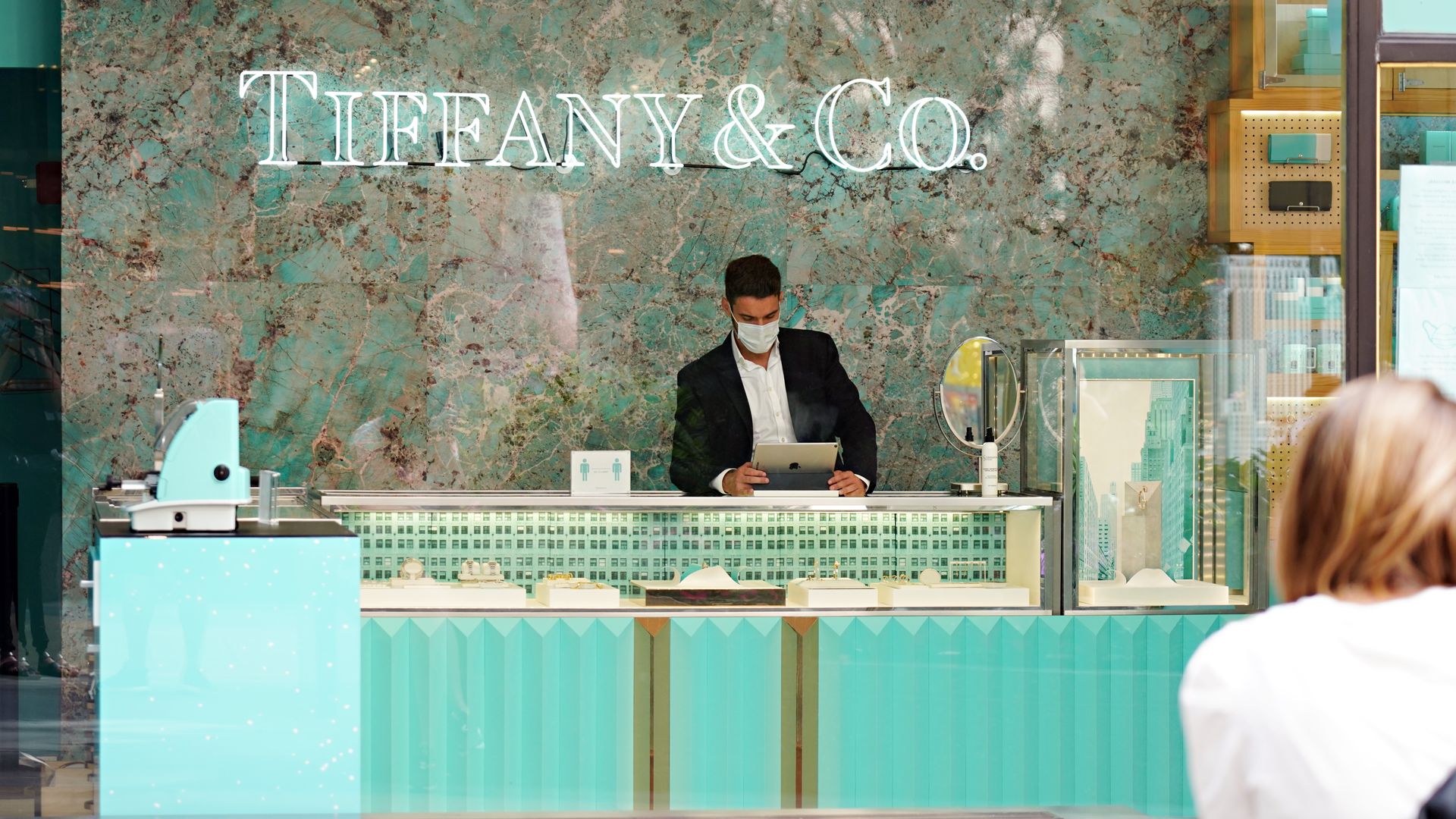 A Tiffany & Co. employee wears a protective mask while selling jewlery