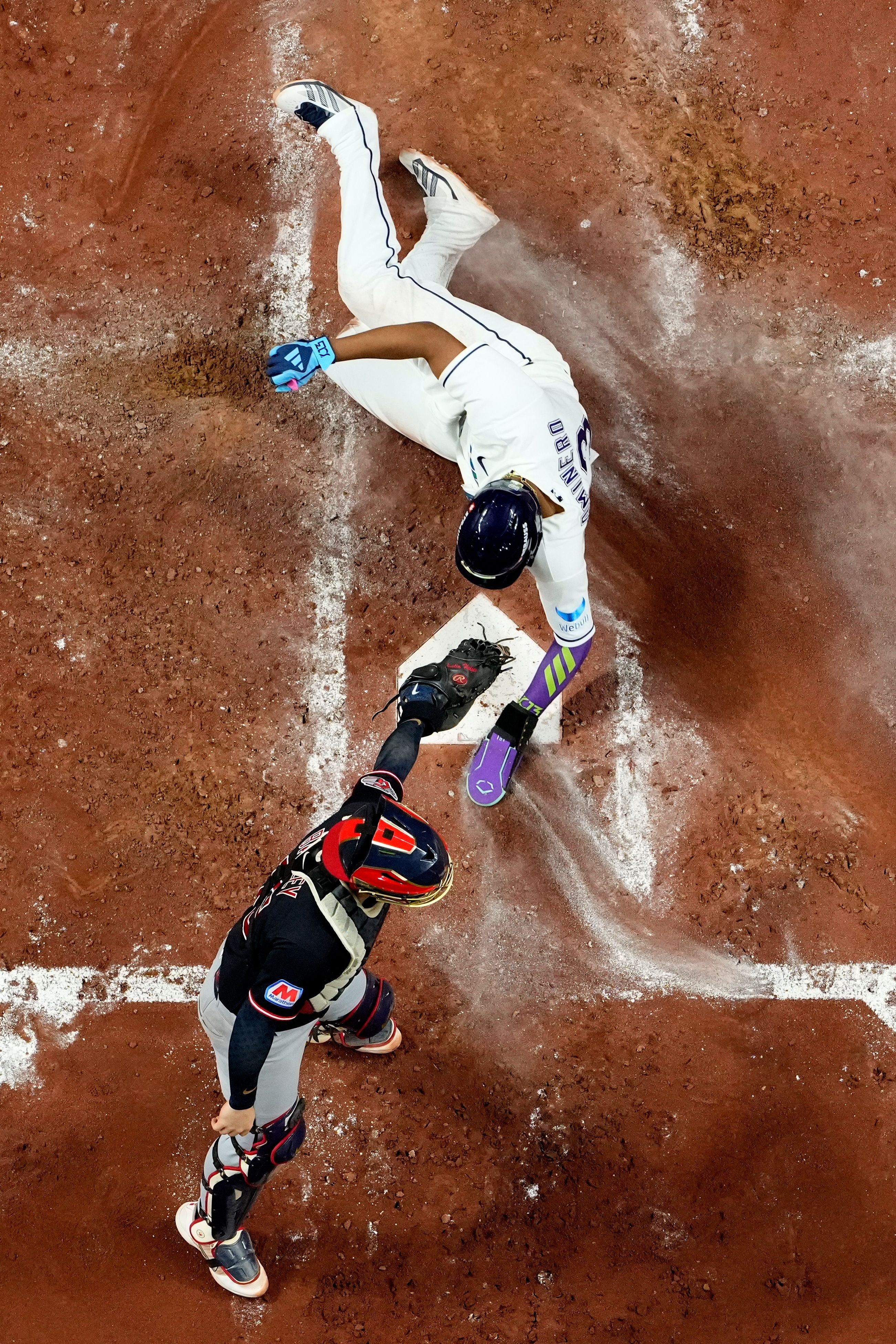 Tampa Bay Rays third baseman Junior Caminero slides into home past Cleveland Guardians catcher Patrick Bailey in Game 6 of the ALCS last night in St. Petersburg, Fla. 