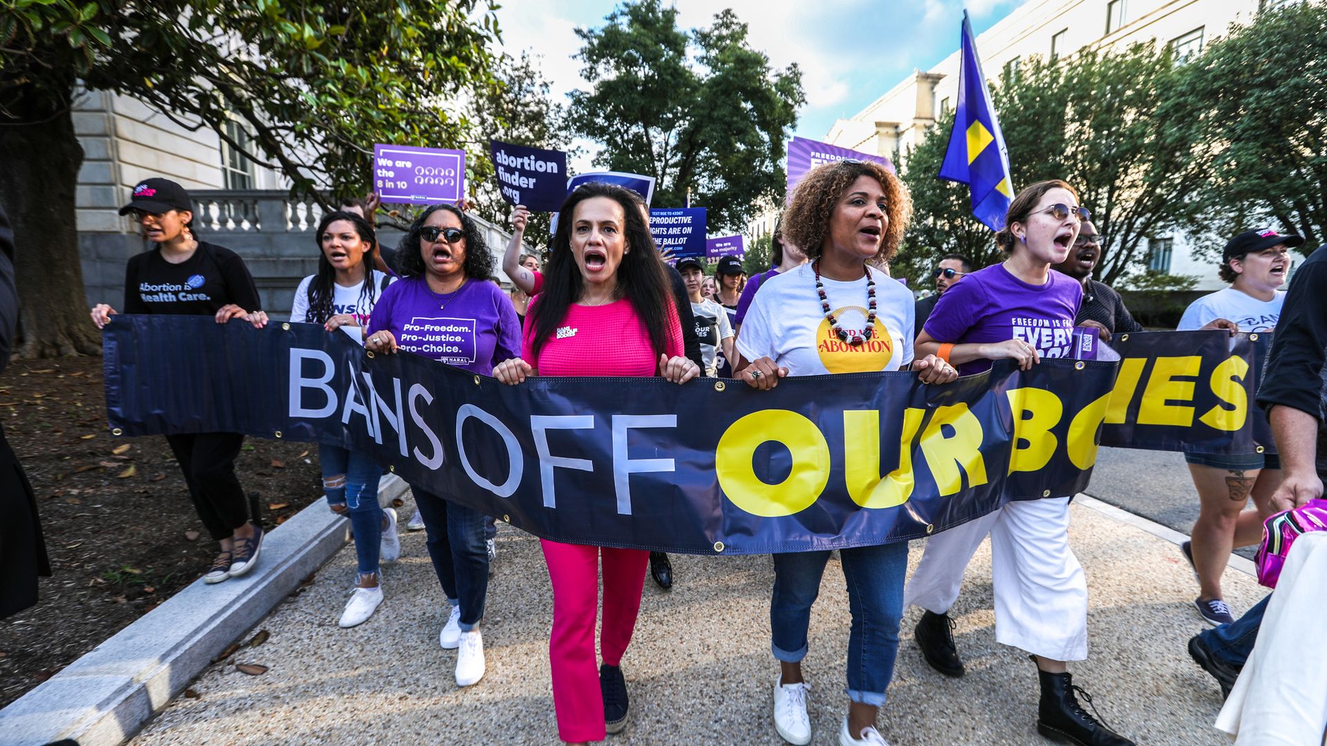 Photo of a row of protesters holding a sign that says "Bans off our bodies"