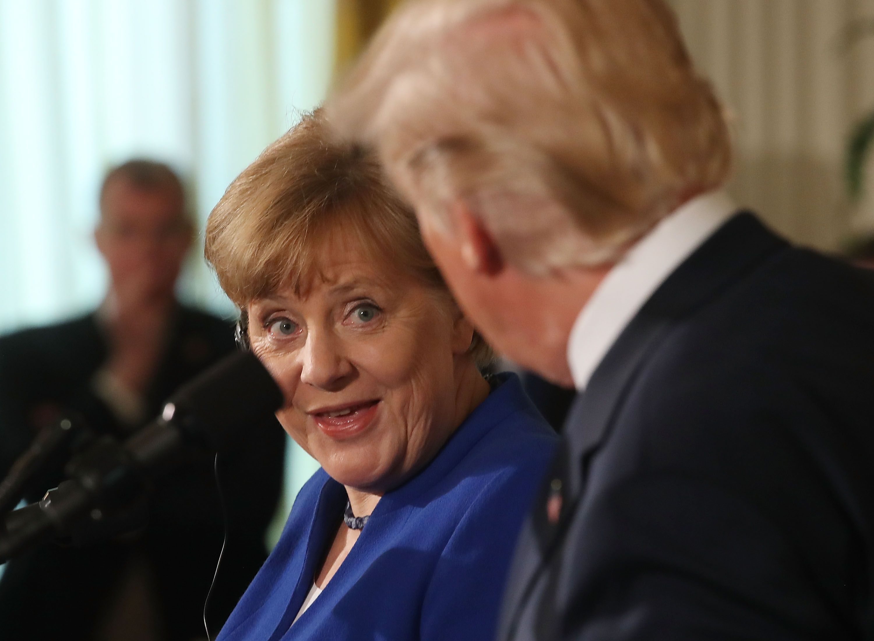 Merkel looks at Trump with surprised expression, mouth agape.