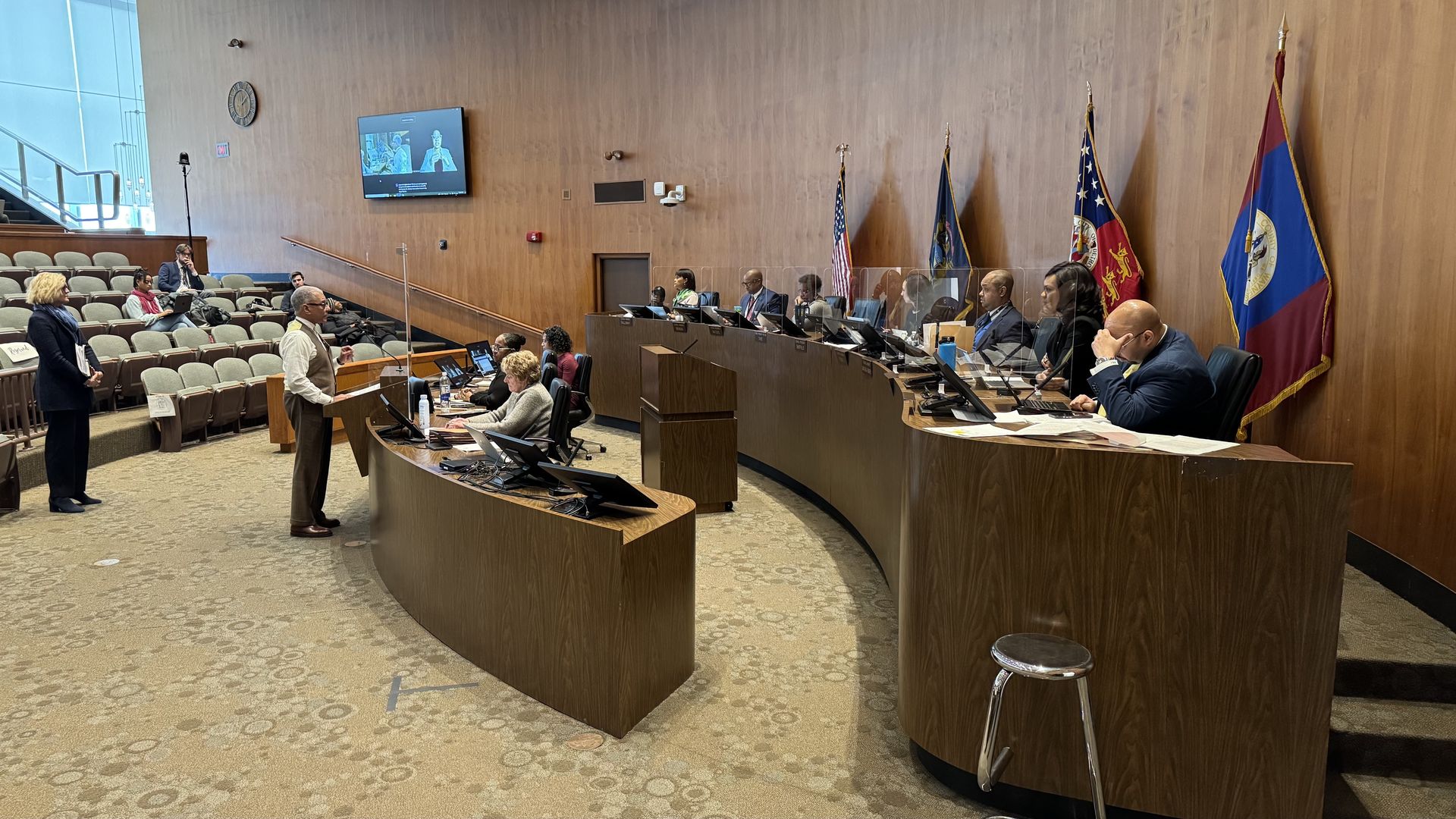 The members of City Council are seated at their table, with a presenter speaking before them.