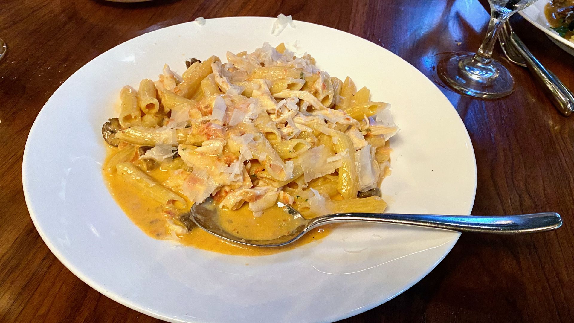Penne pasta in a white dish covered in an orange sauce and shredded mozzarella cheese