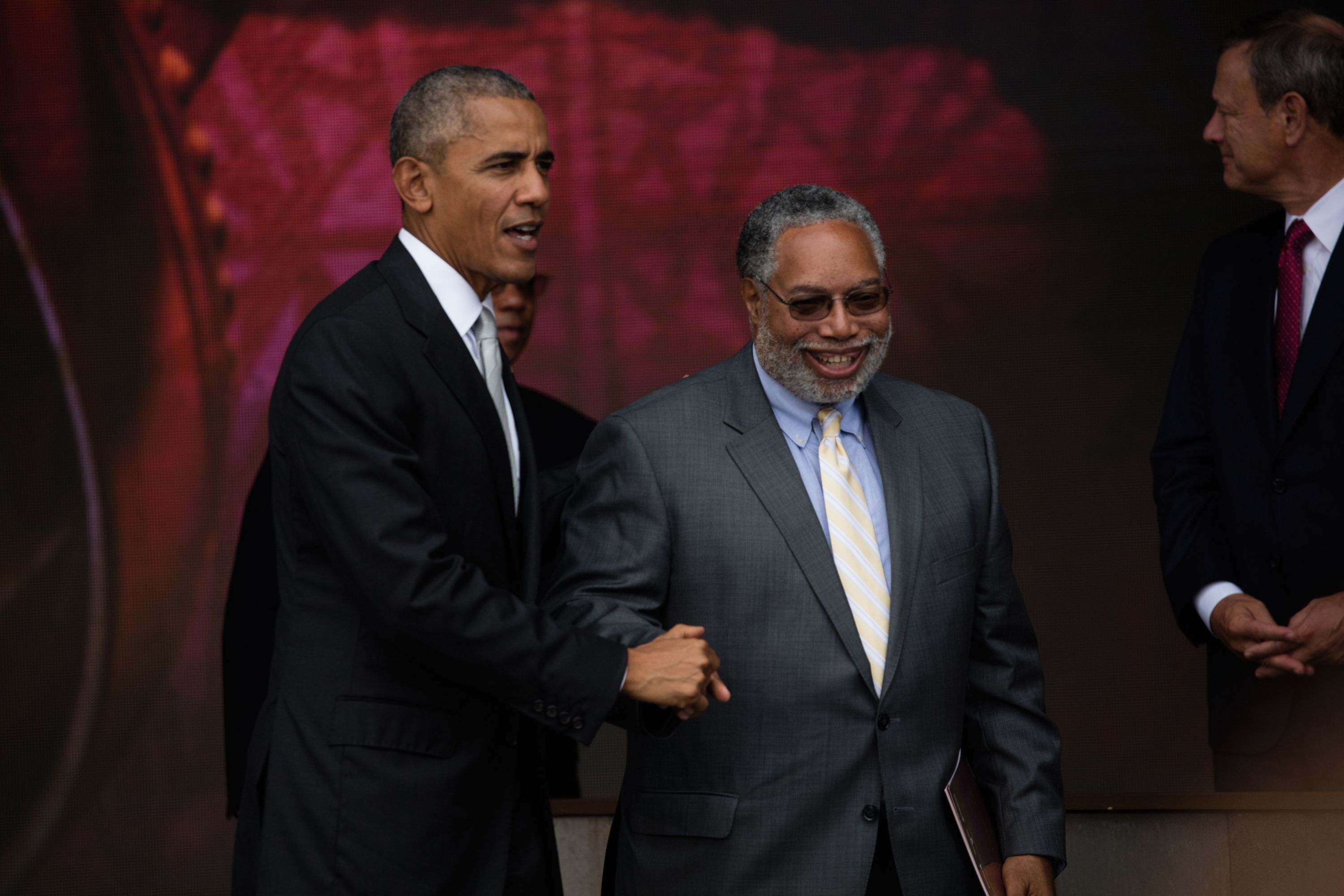 View of President Barack Obama (left) and founding director Lonnie Bunch as they clasp hands at the opening of the National Museum of African American History and Culture, Washington DC, September 24, 2016. (Photo by David Hume Kennerly via Bank of America/Getty Images)
