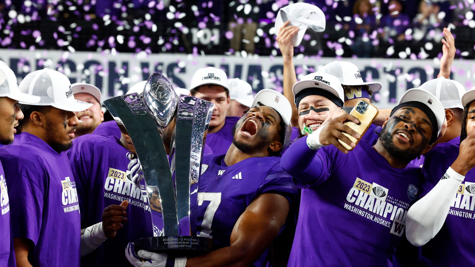 Football players in purple uniforms celebrate on the field after a win. 