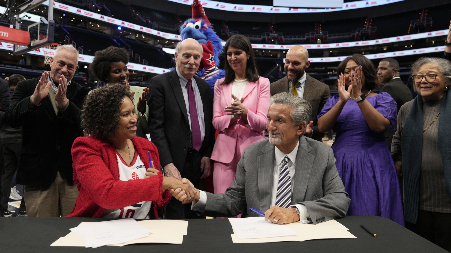 Monumental Sports CEO Ted Leonsis (right) shakes hands with Mayor Muriel Bowser after signing an agreement on the court before a Washington Wizards game at Capital One Arena.