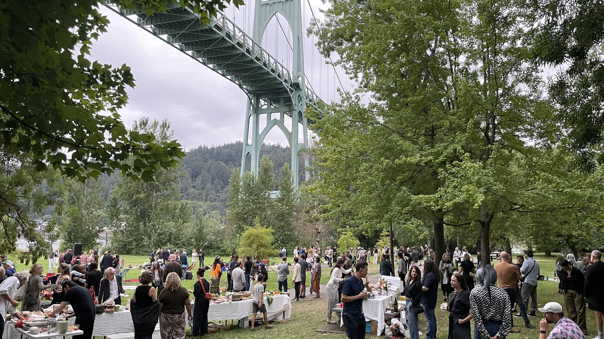 A photo of people standing under a copper-colored bridge.