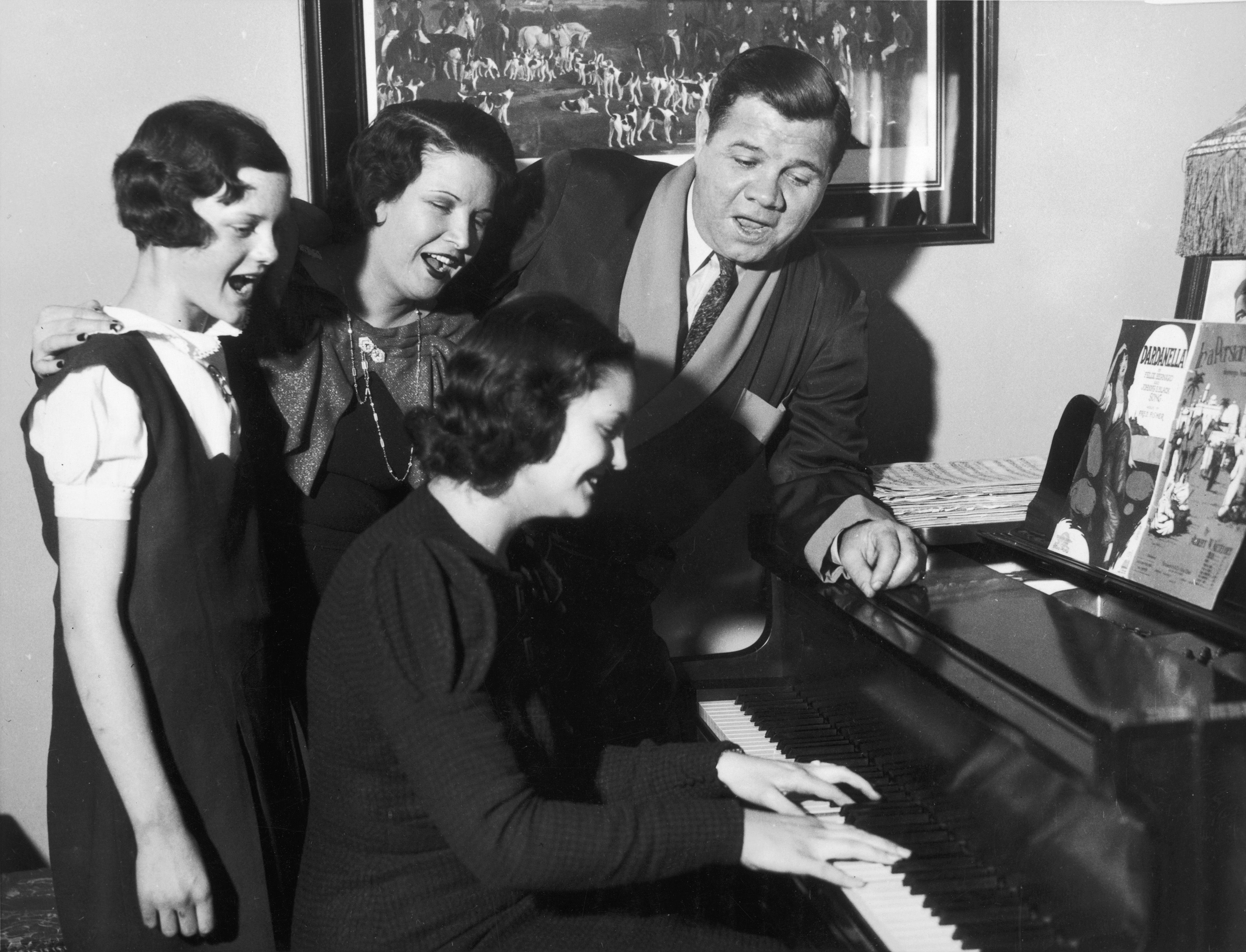An old photo of Babe Ruth and his family singing by the piano