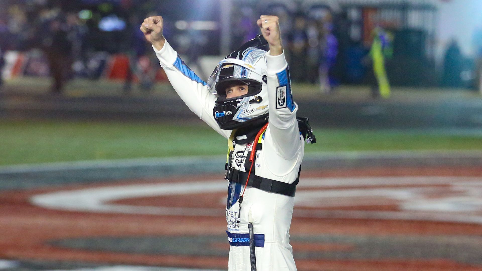 kyle larson wins coca cola 600 stands with arms up in the air in celebration