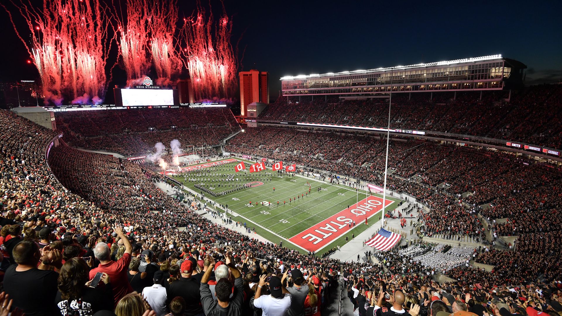 An overview of Ohio Stadium as the Ohio State football team takes the field and red fireworks launch