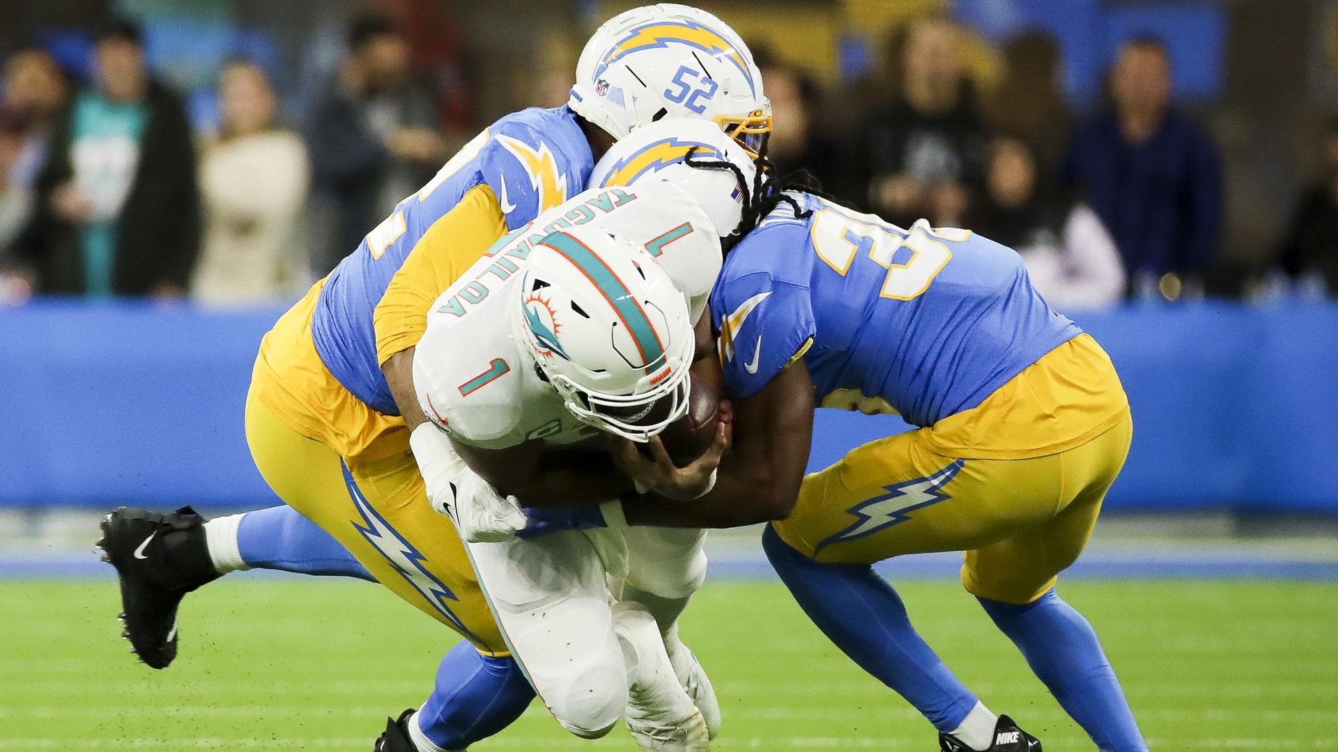 Dolphins quarterback Tua Tagovailoa is sacked by two Chargers defenders.