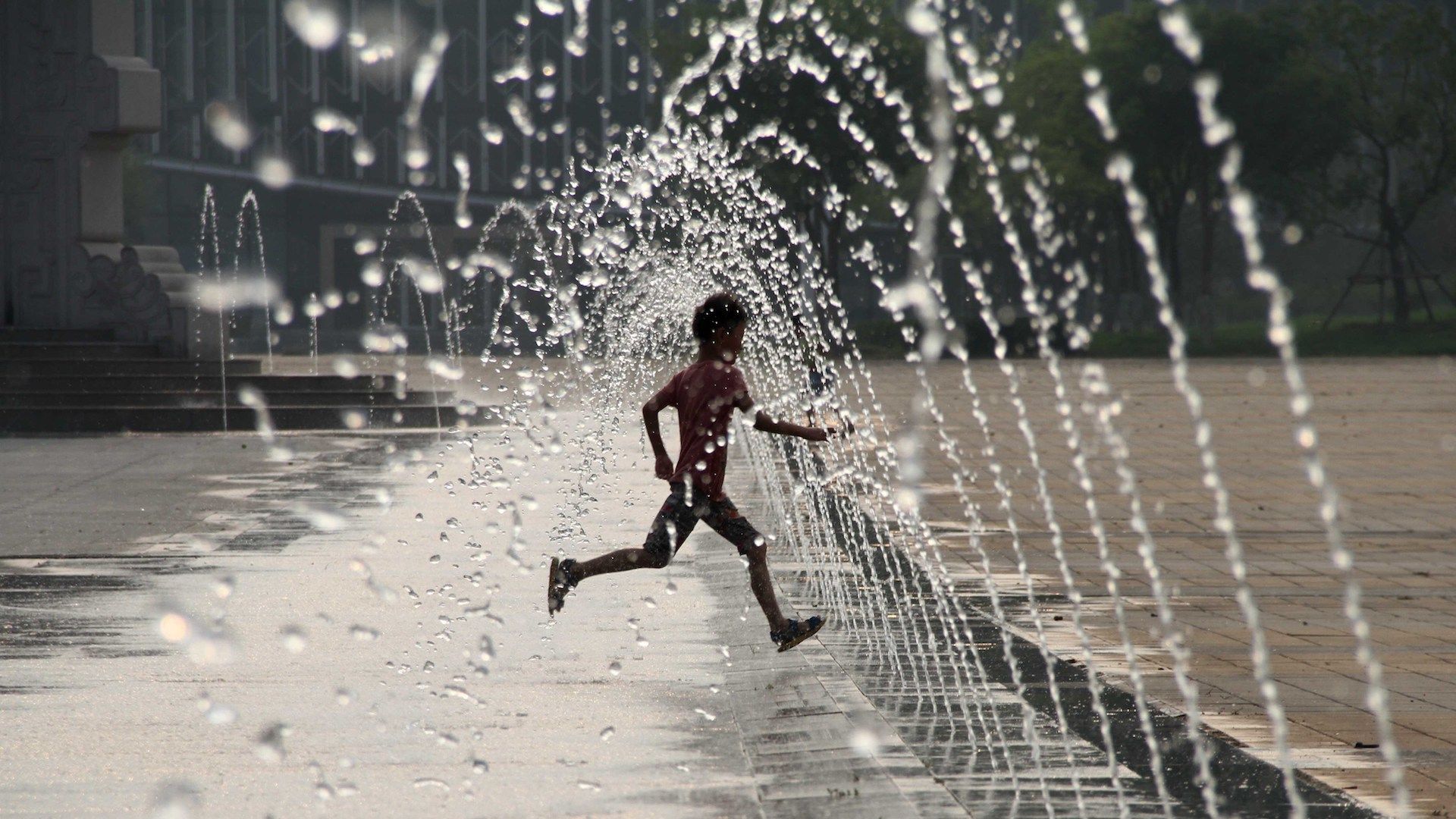 Photo of a child running through a water fountain during a heat wave in eastern China.