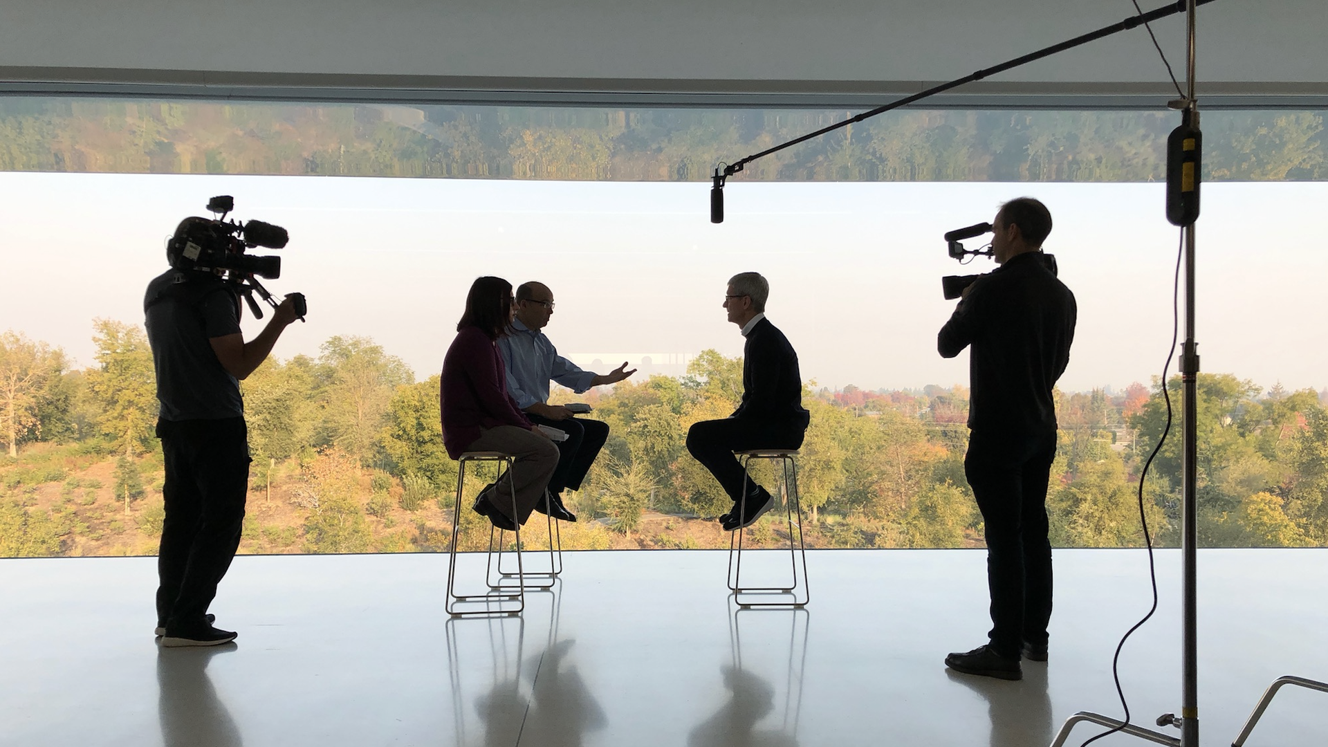 Tim Cook, seen largely in silhouette, being interviewed by Axios' Ina Fried and Mike Allen at Apple Park