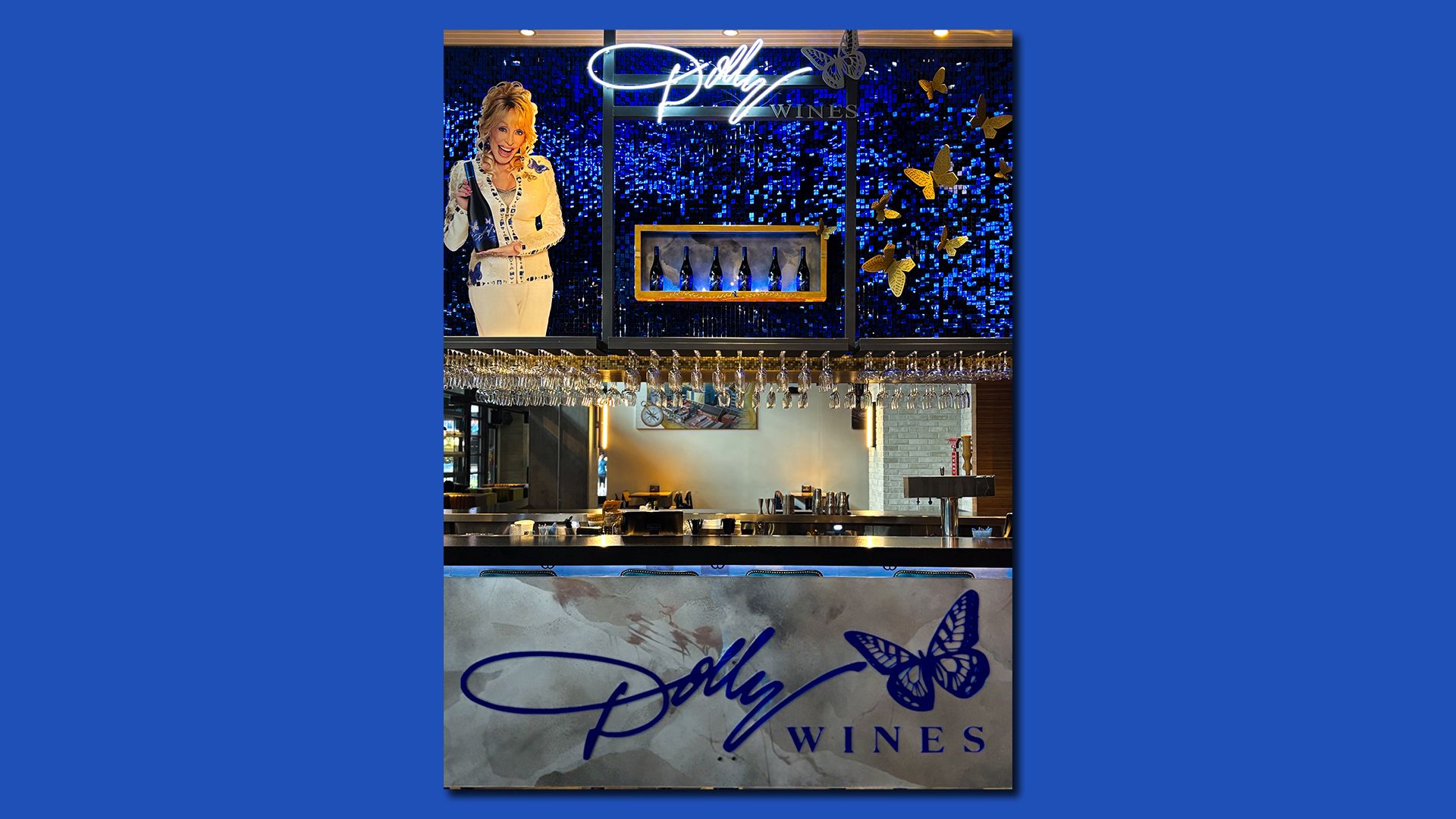 Wine bar with Dolly Wines branding, featuring a blue sequin backdrop, illuminated Dolly signature, butterflies, wine bottles, glasses, and a bar counter with a butterfly logo.