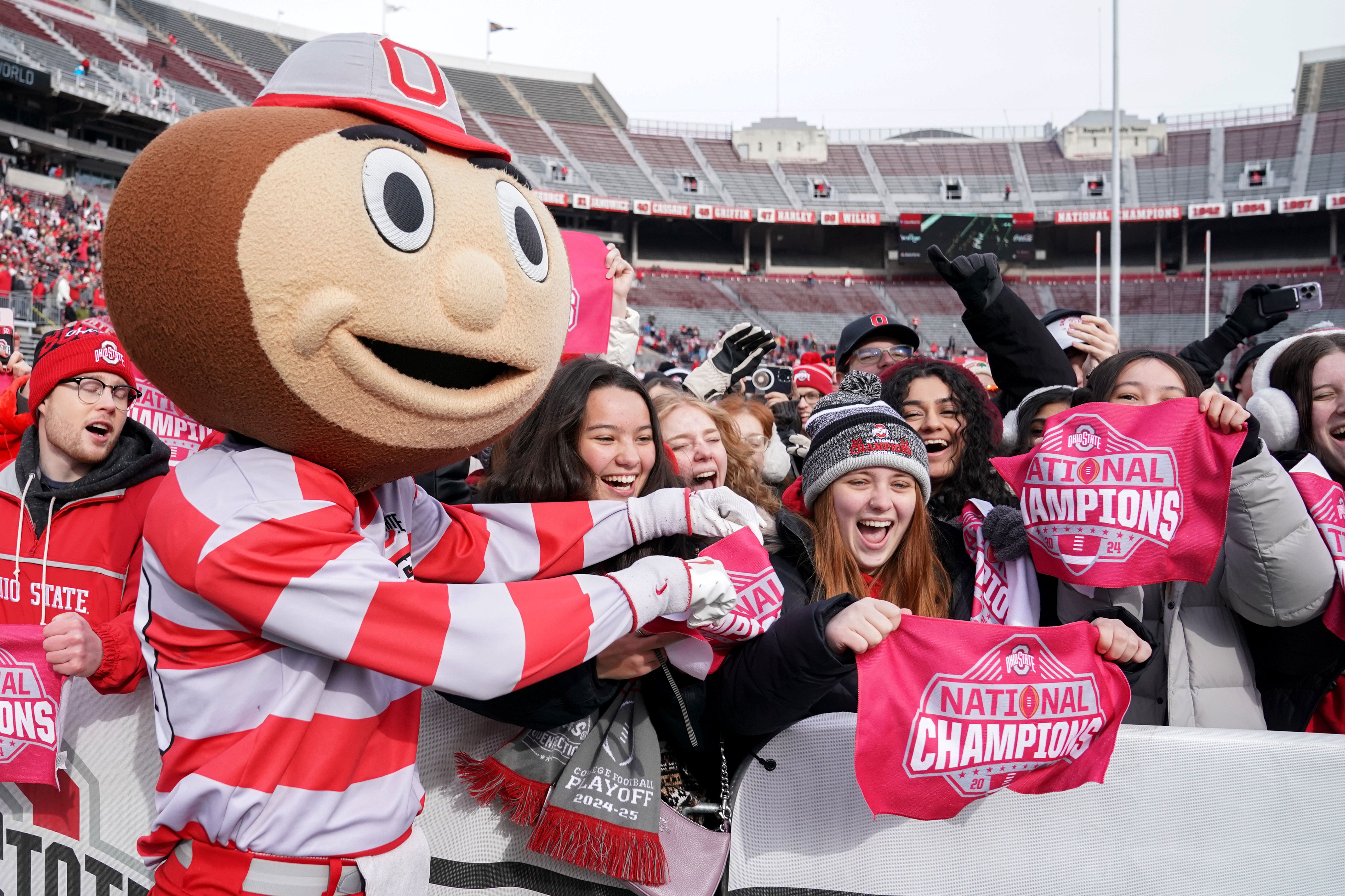 Brutus Buckeye celebrates with fans before the celebration at Ohio Stadium, holding towels that say "National Champions"
