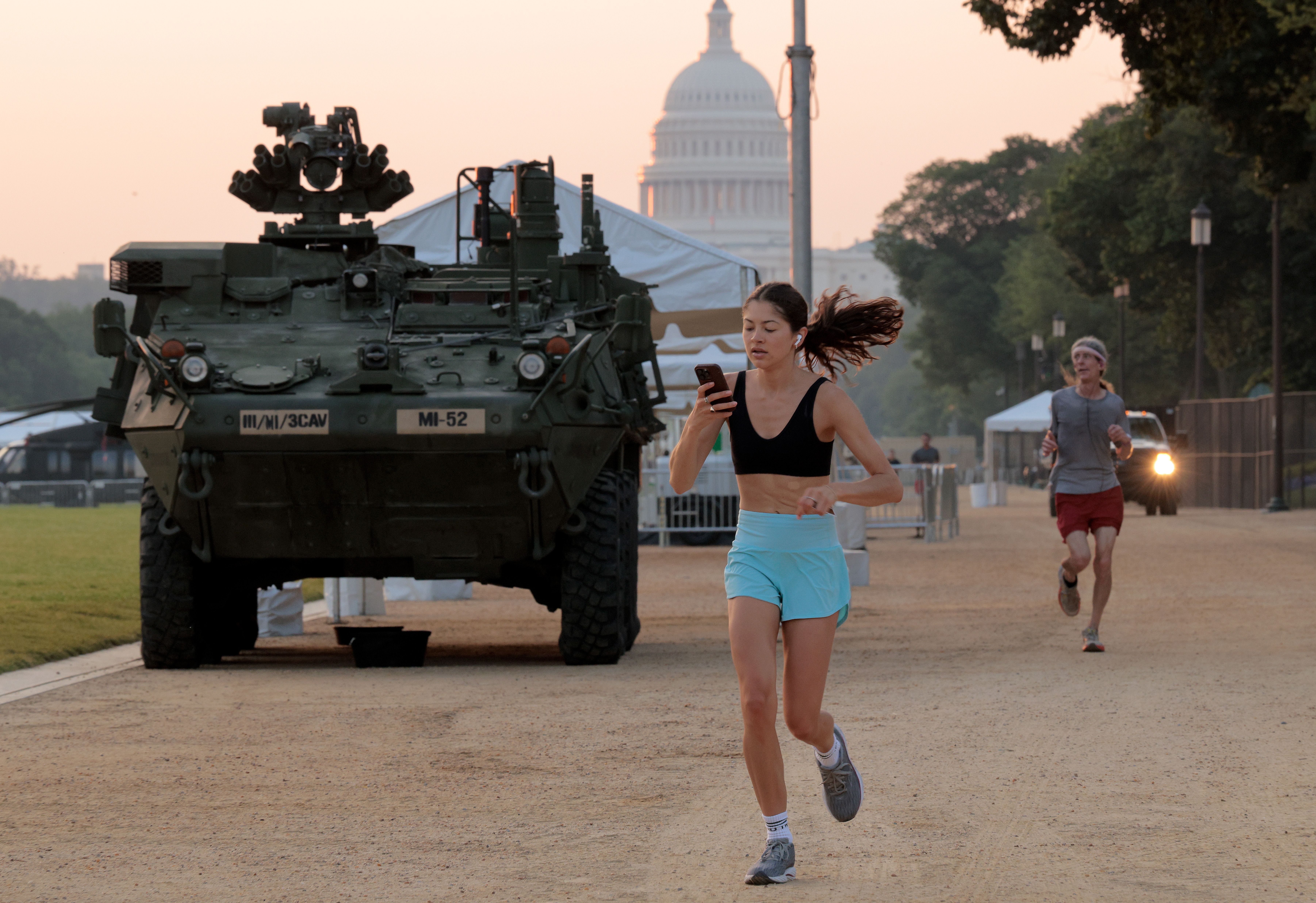 A photo of a runner on Washington, D.C.'s National Mall, with an Army combat vehicle in the background.