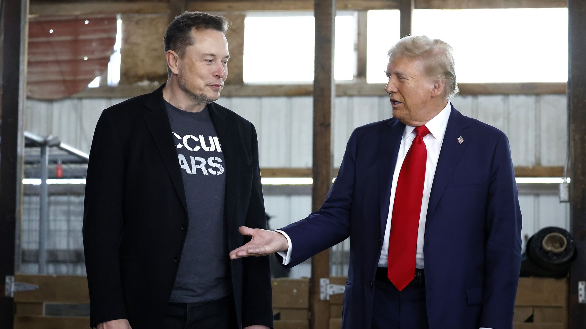 Elon Musk stands next to President Donald Trump