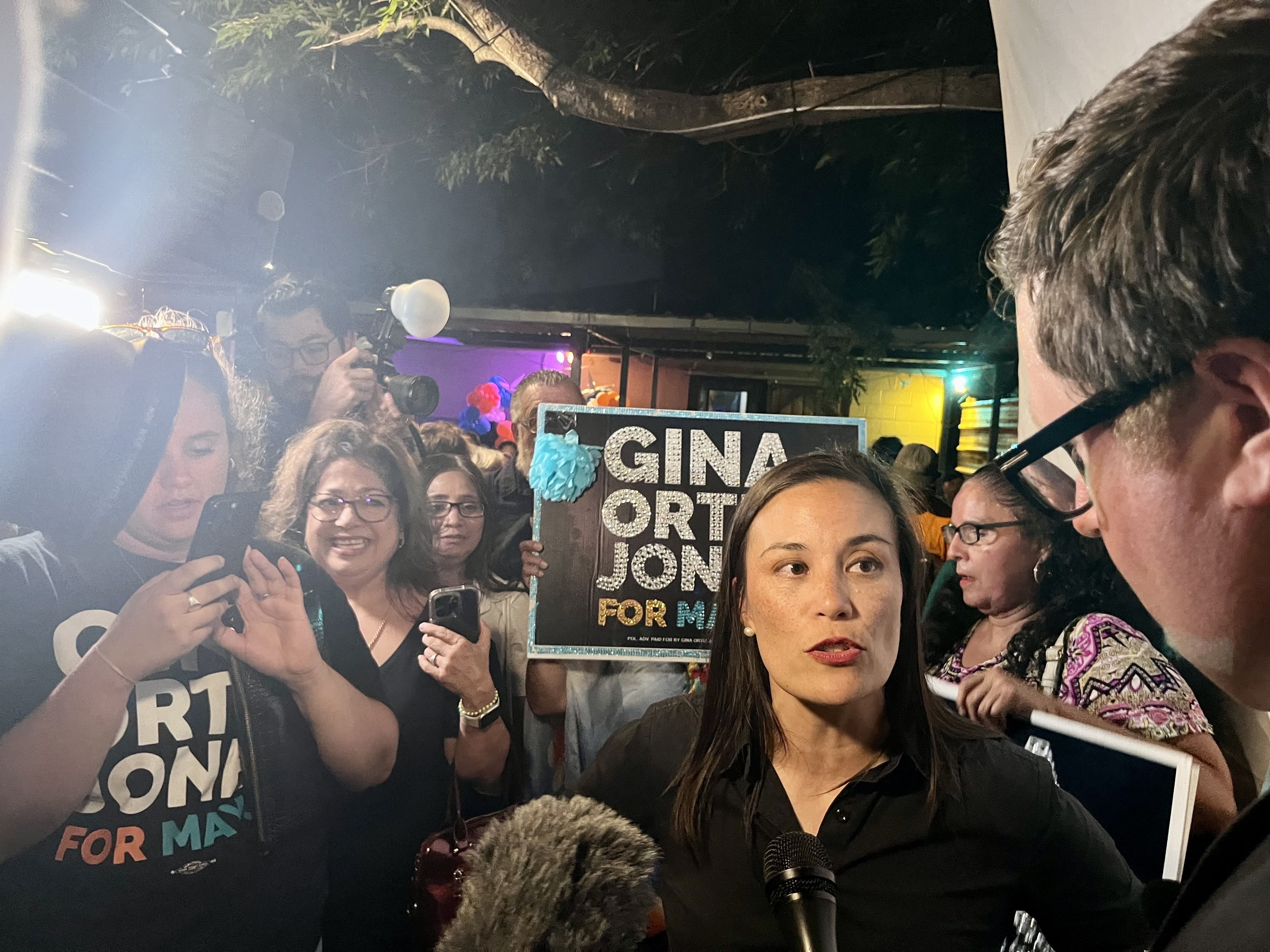 San Antonio mayor-elect Gina Ortiz Jones stands in front of a crowd looking to the side 