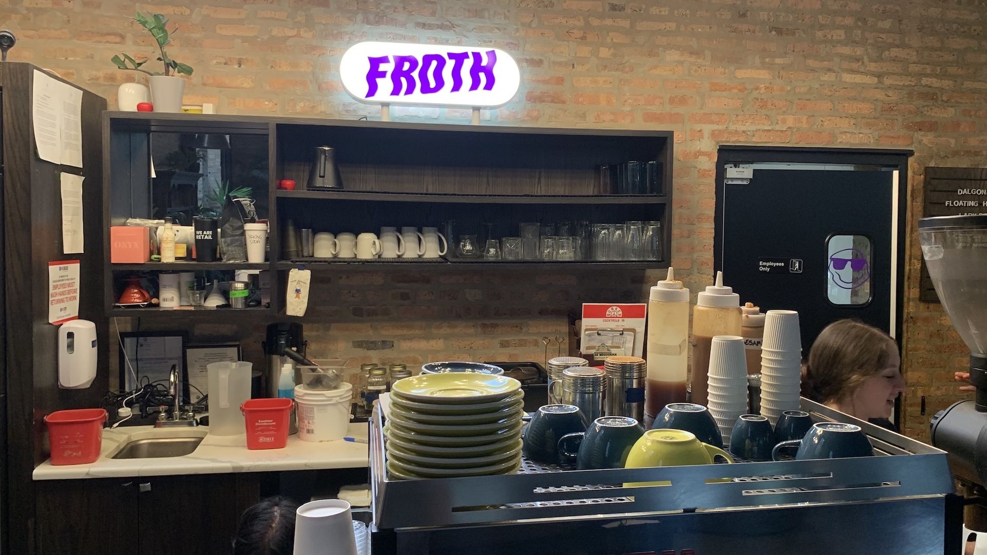 Coffee bar with a brick wall and purple sign that reads: Froth in squiggly font