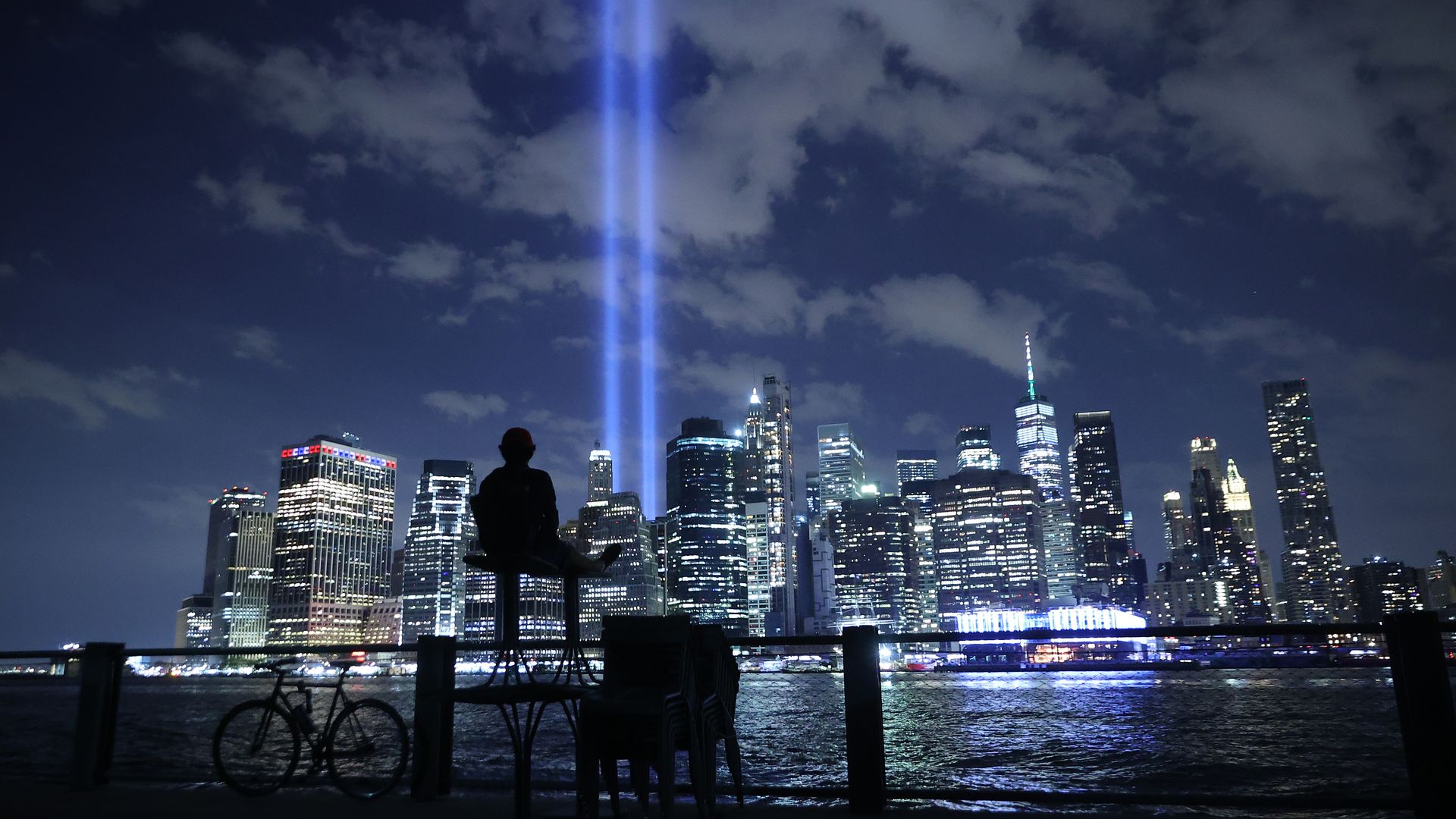 A person watches the Tribute In Light shine into the sky from Lower Manhattan during a test on September 07, 2021 in New York City. 
