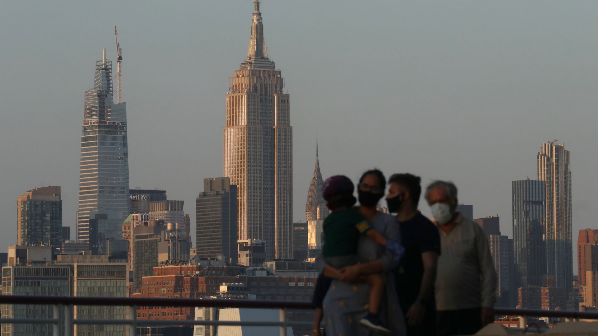Family members all wear masks as they walk along the Hudson Rive