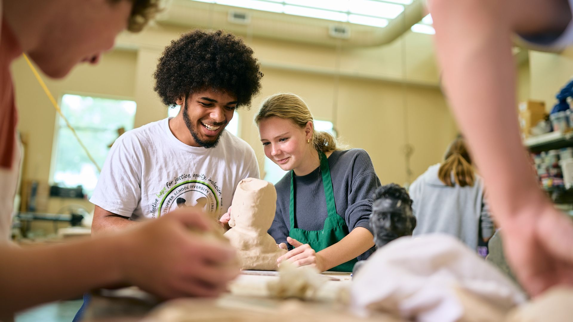 A man and a woman working on a clay art piece.