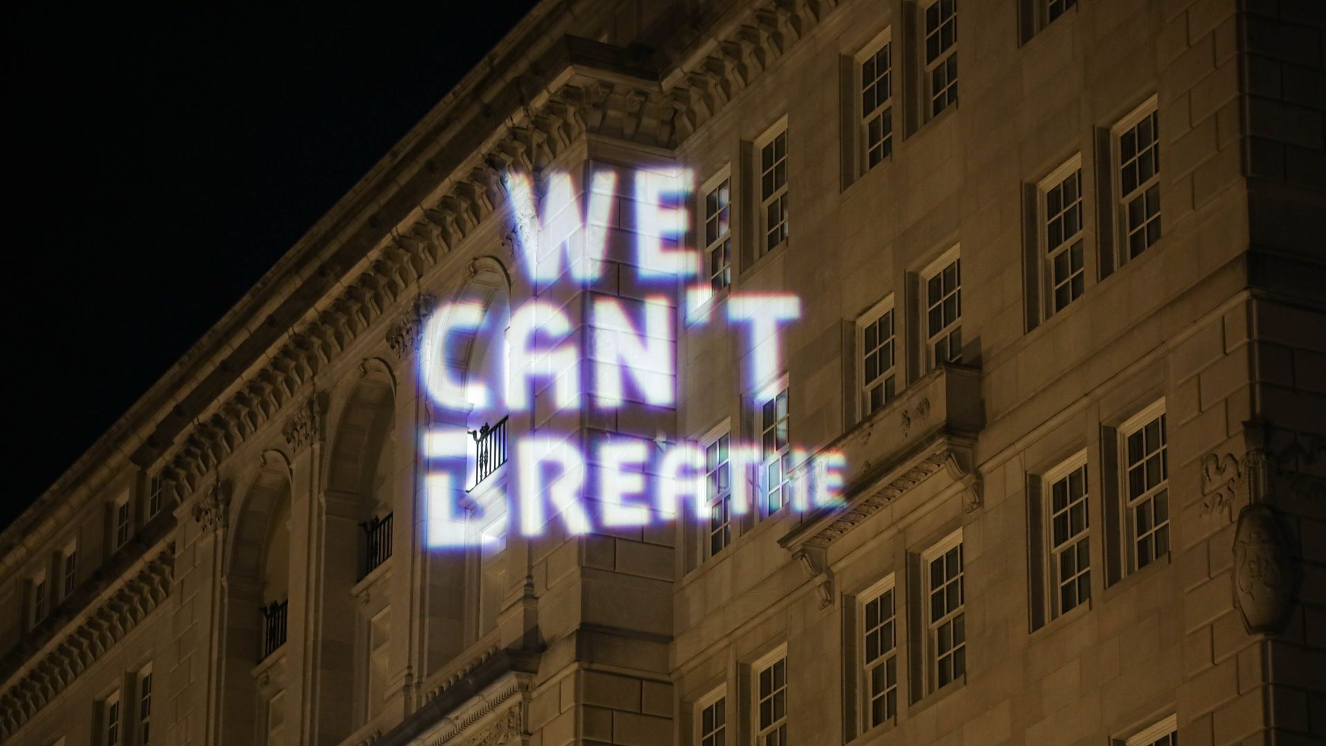 Projected text reading with "We can't breath" demonstrated by protesters
