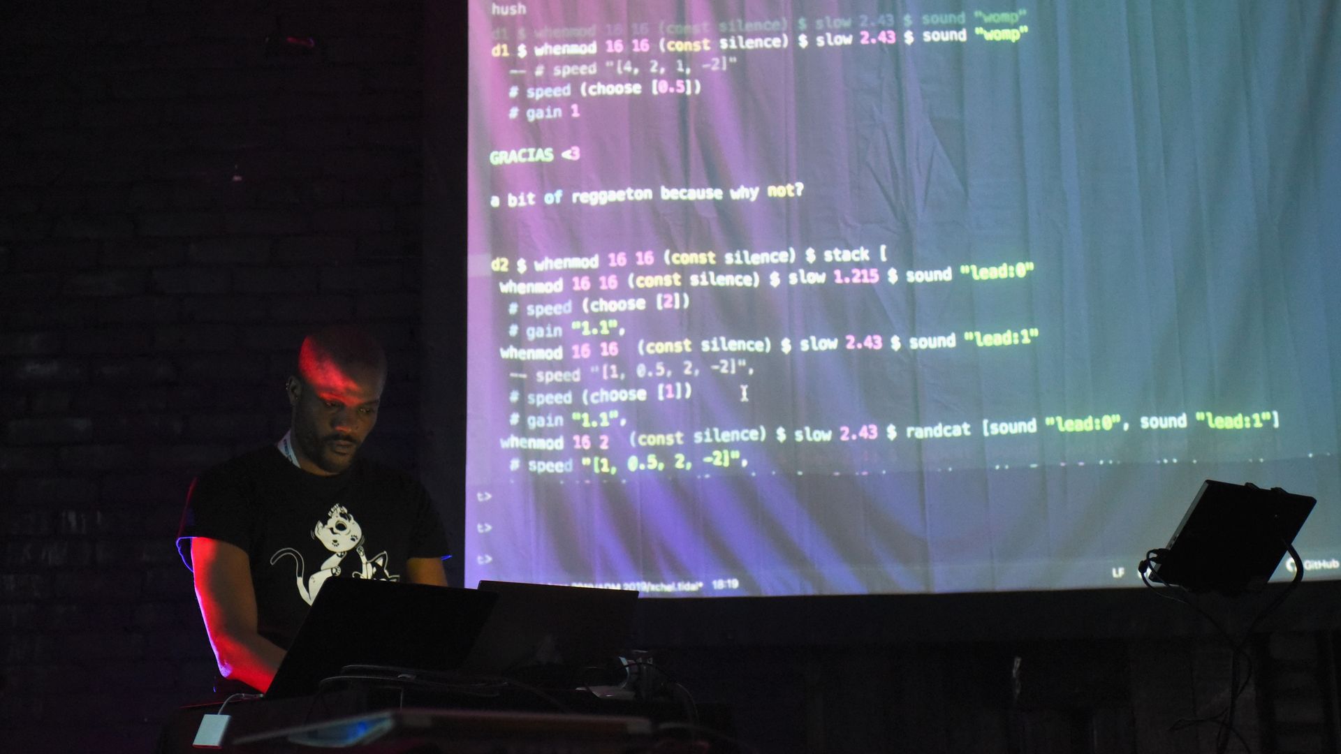 Photo of a man working at a laptop with code projected on a screen
