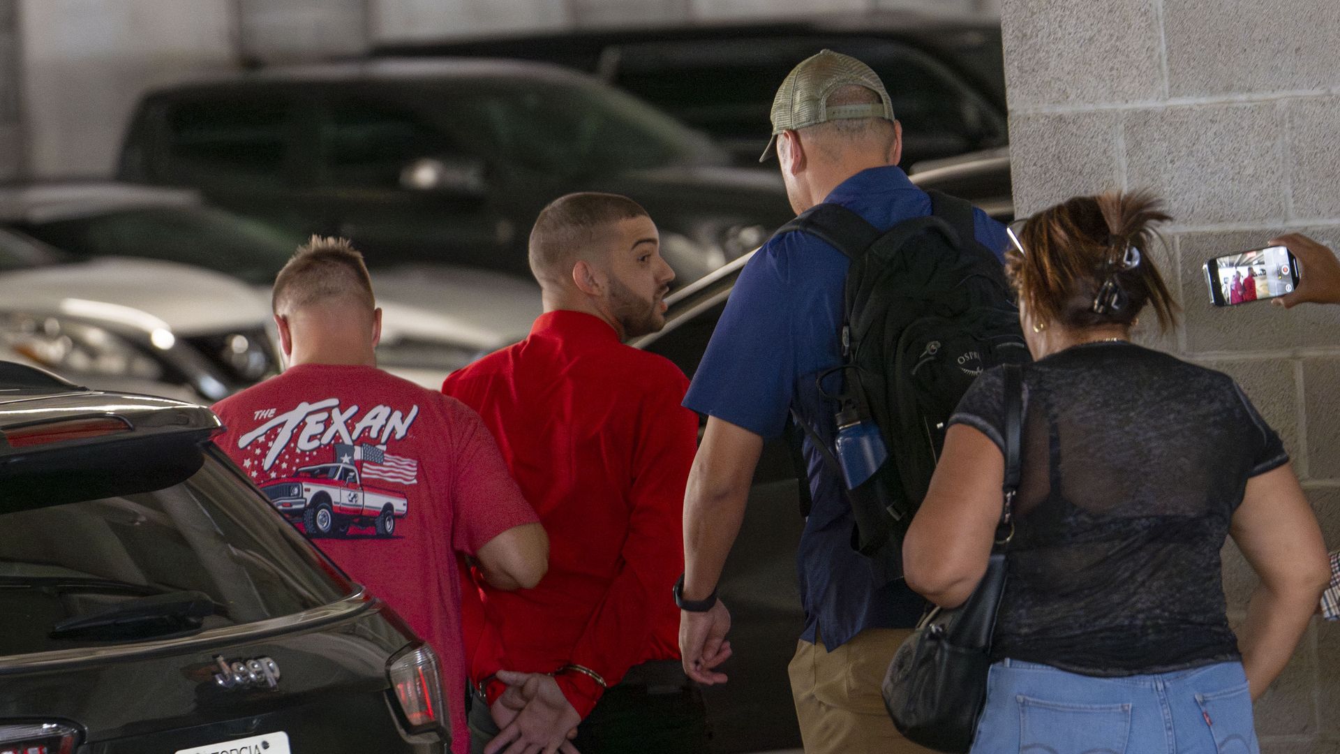 ICE agents lead a man in handcuffs from the entrance of the Federal Building where the immigration court resides on the tenth floor in Houston