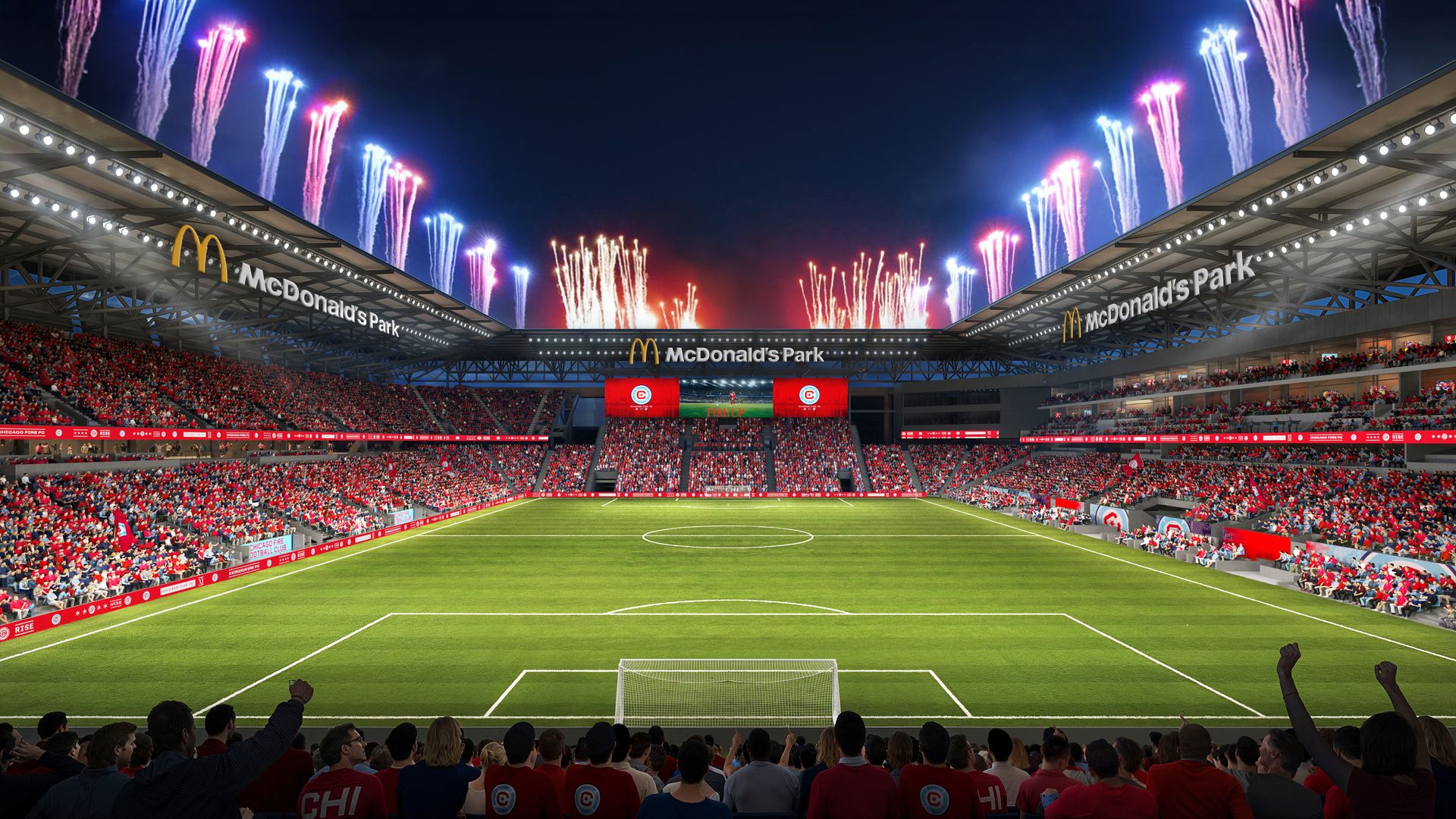 Nighttime stadium at McDonald's Park with a packed red-clad crowd, a soccer field in the foreground, and bright colorful fireworks exploding above the stands and sky.