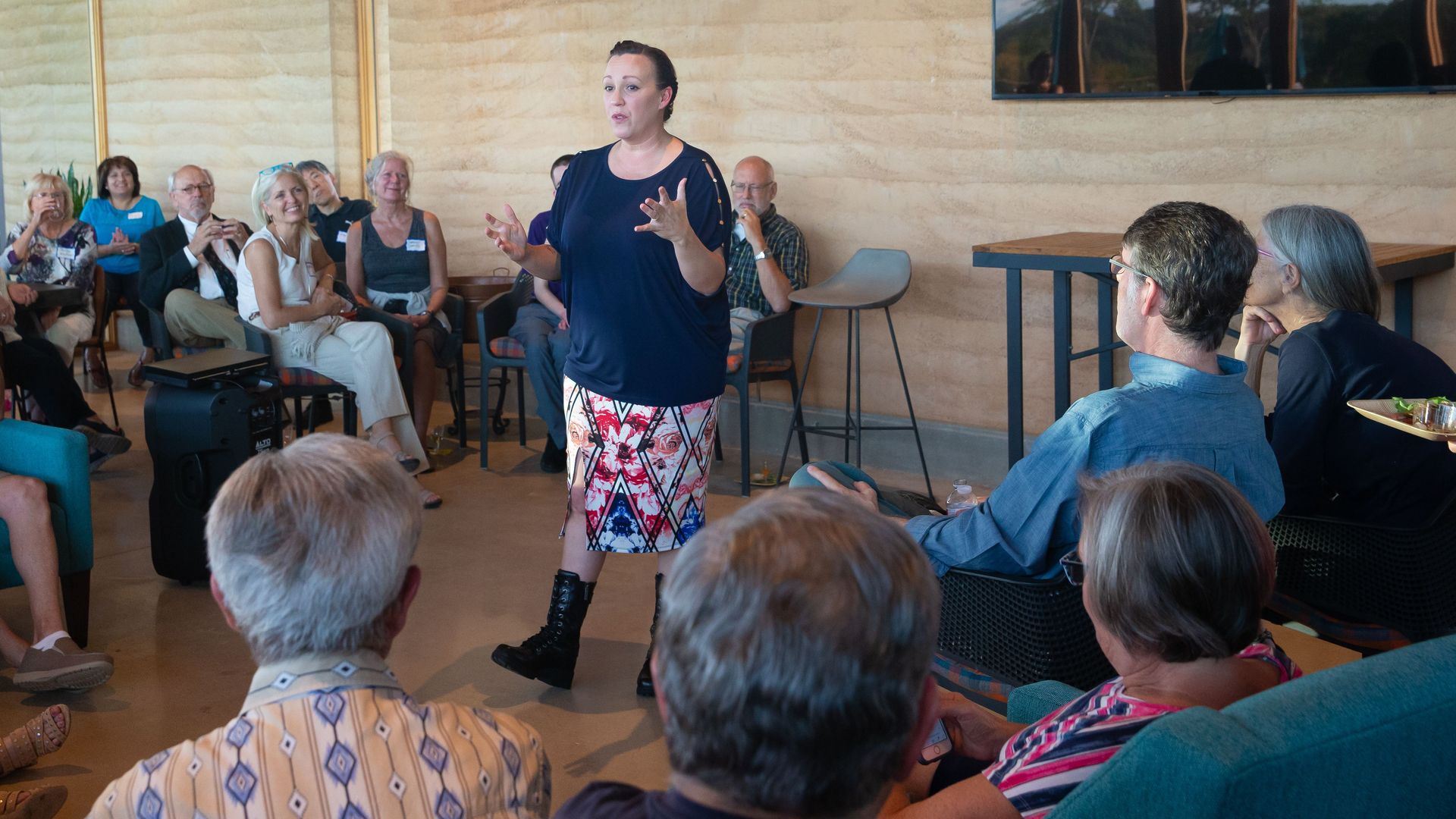 In this image, Hegar stands and gestures while speaking in the middle of a seated circle of constituents. 