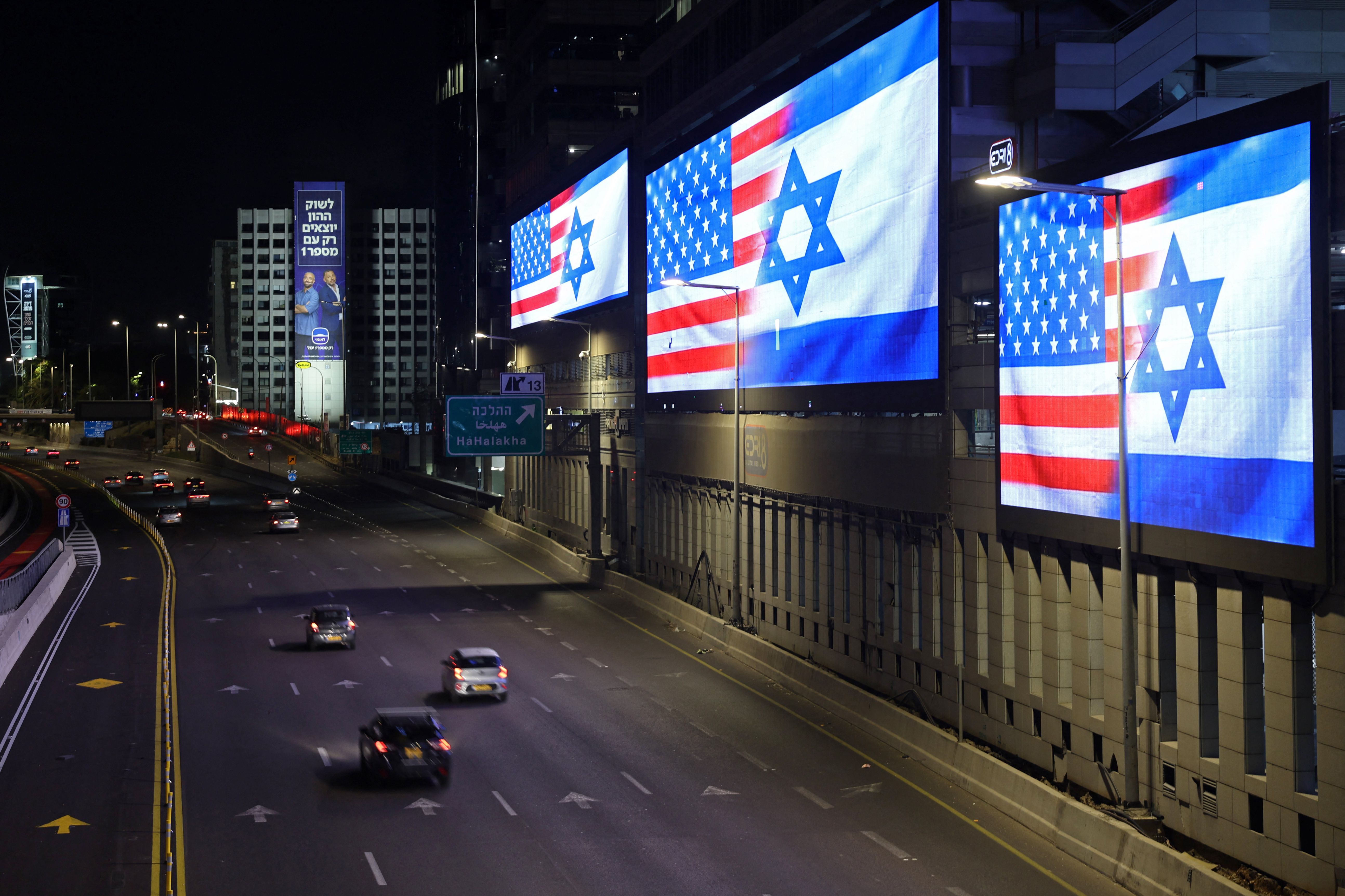 Traffic moves past the giant screens installed along the highway displaying the national flags of US and Israel, in Tel Aviv on March 4, 2026.