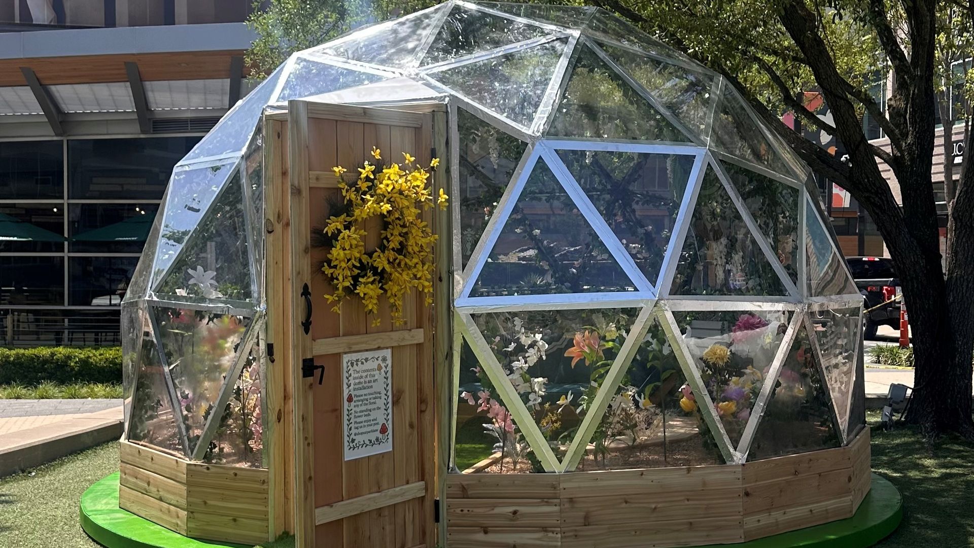 A photo of a large clear globe that people can walk into filled with flowers 