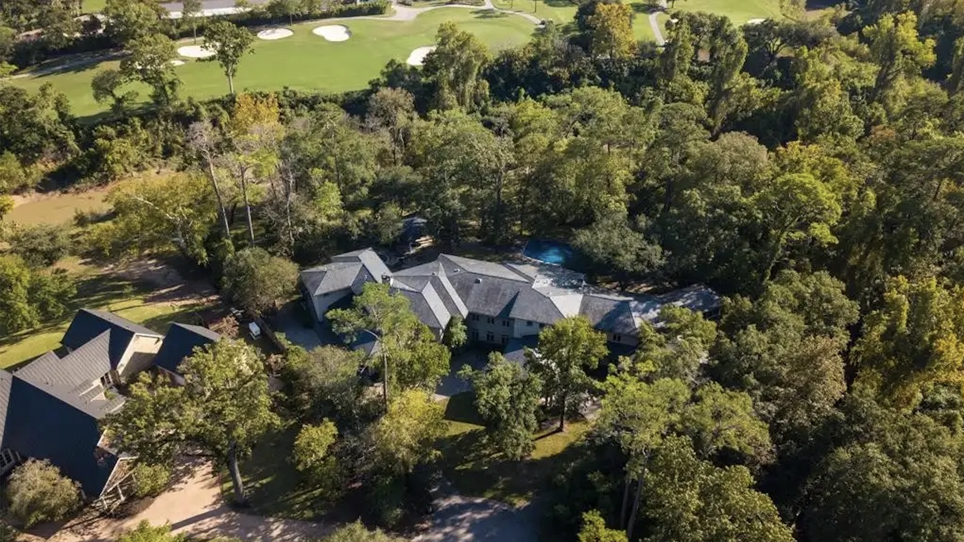 Photo of a house with a gray roof surrounded by trees. 