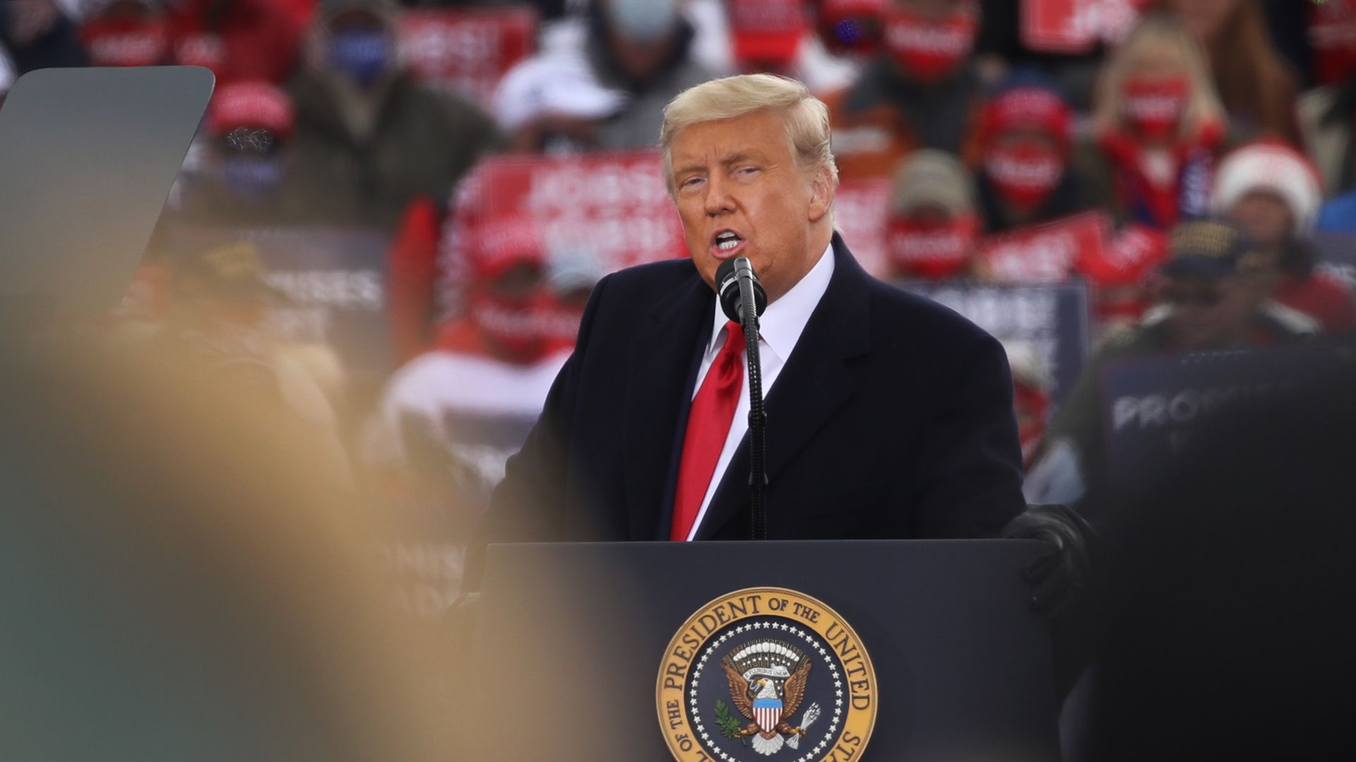 Photo of Donald Trump speaking behind a podium at a rally