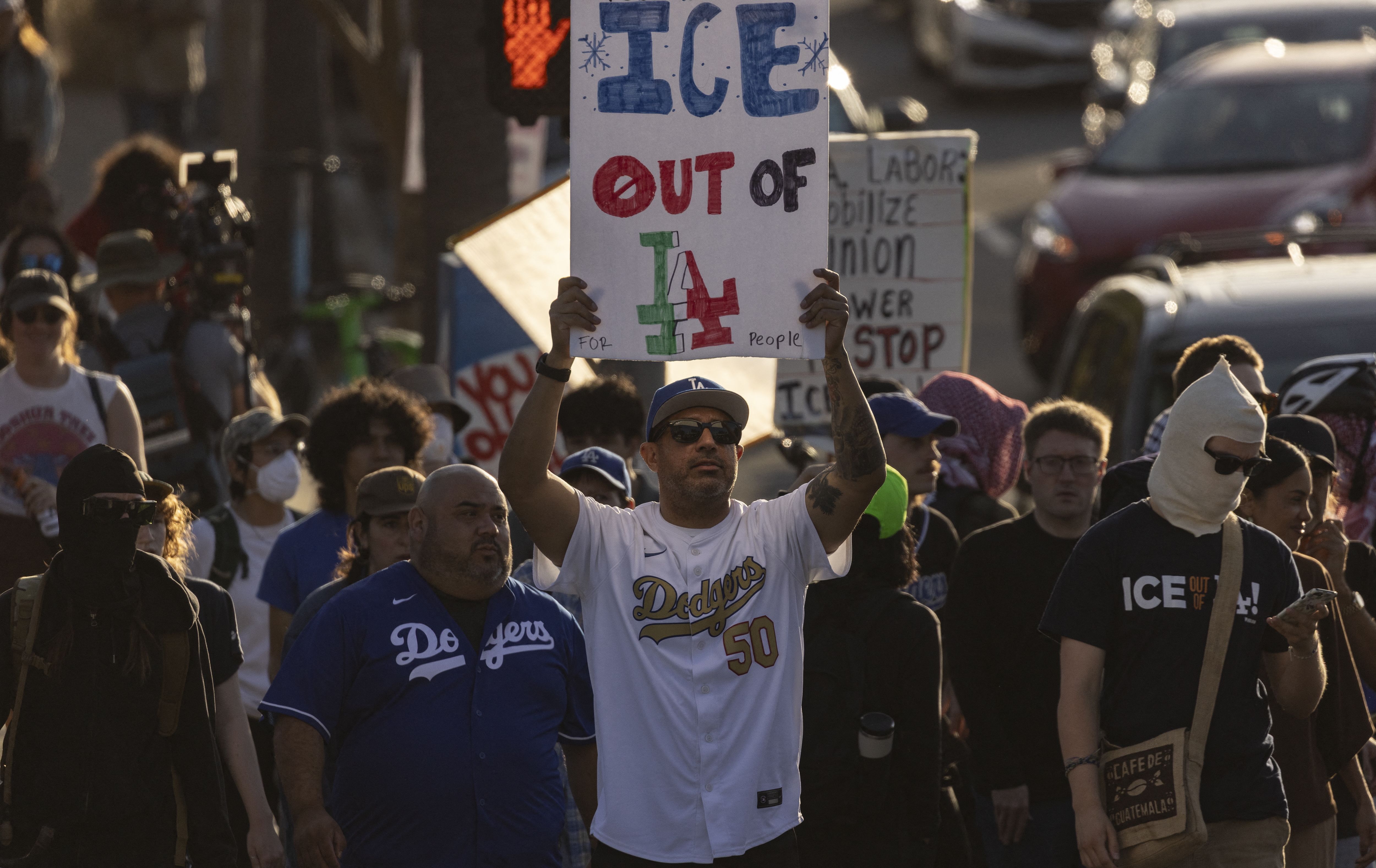 A demonstrator holds up a sign as they protest in front of the main entrance of Dodger Stadium to call for a boycott of the team, claiming the organization supports federal immigration efforts, in Los Angeles, on June 19, 2025.