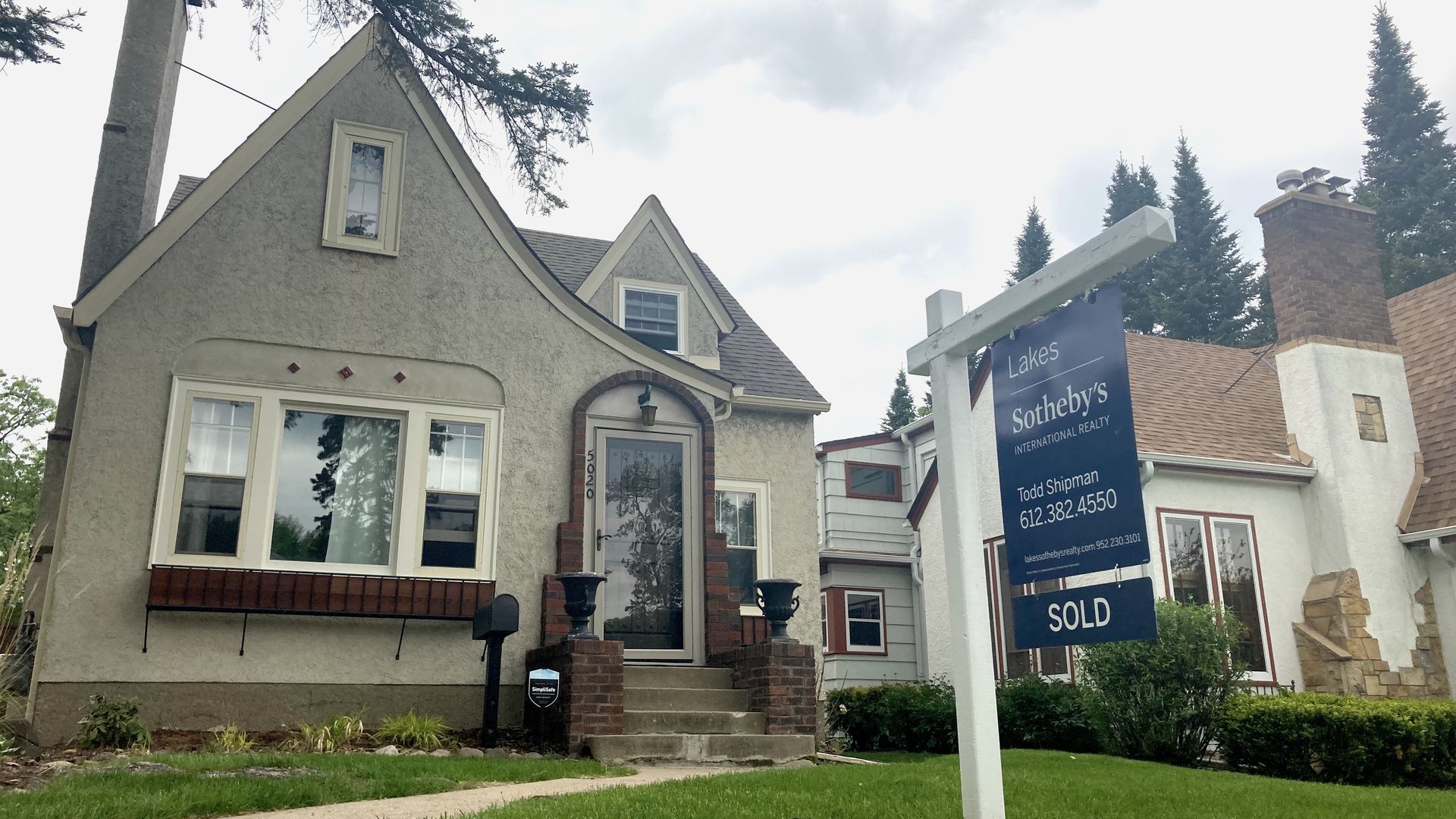 A for sale sign in front of a stucco home 