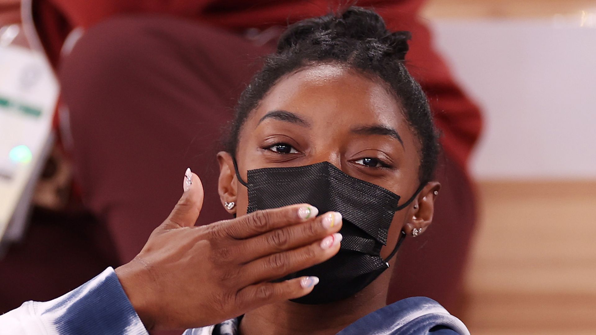 Simone Biles of Team United States blows a kiss whilst watching the Men's All-Around Final on day five of the Tokyo 2020 Olympic Games at Ariake Gymnastics Centre on July 28, 2021 in Tokyo, Japan