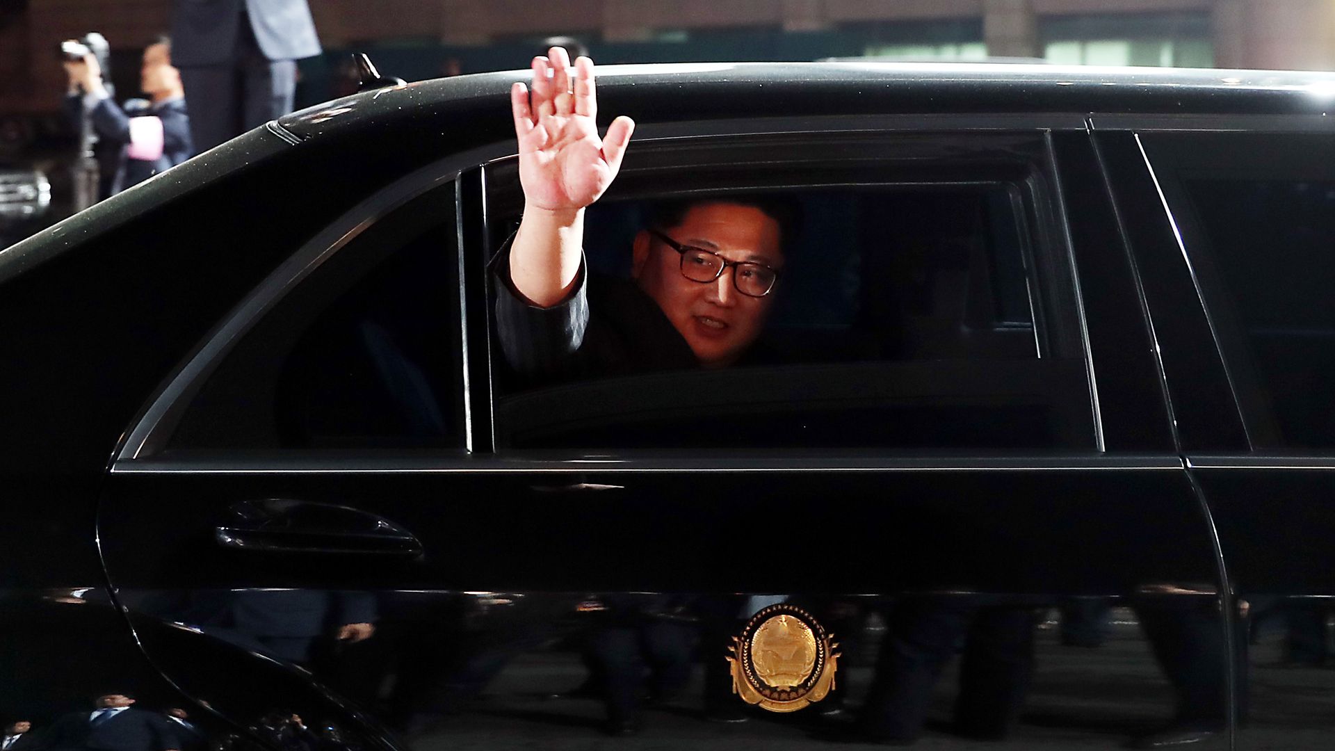 Kim Jong-un waves from a black limo.