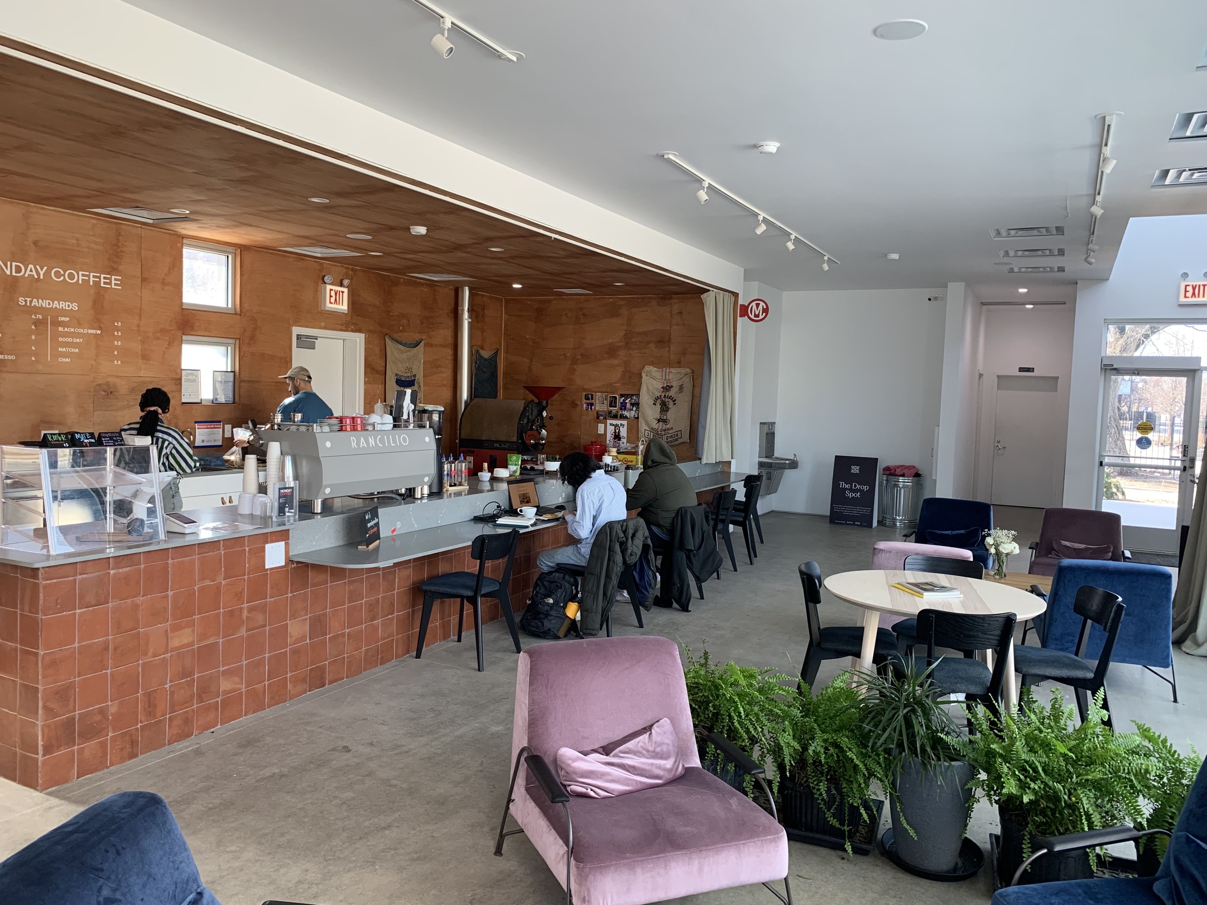 Photo of a coffee shop with lounge chairs and plants. 