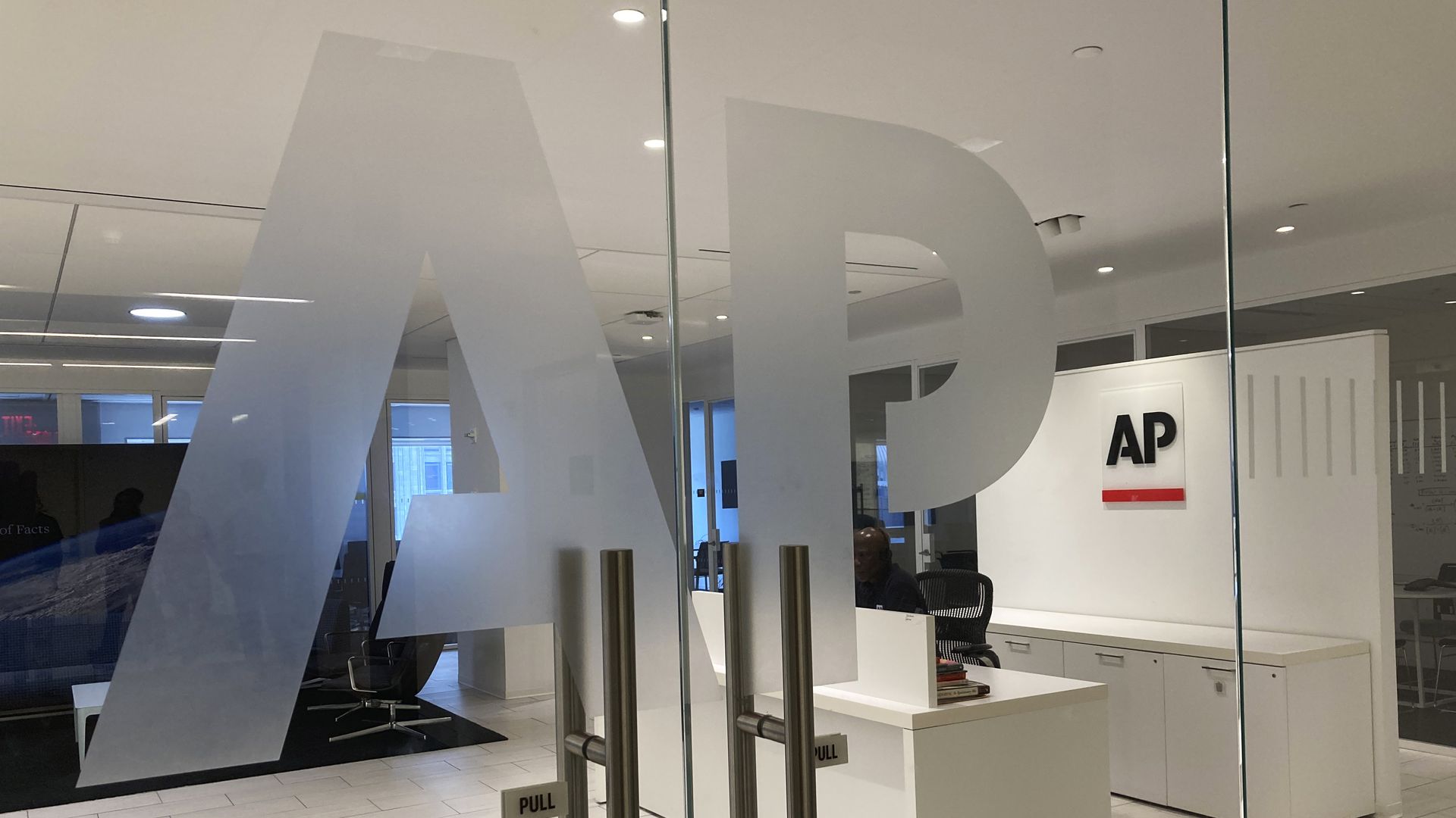 Photo of the Associated Press office entrance, with large frosted “AP” letters on glass doors and a reception desk visible inside.