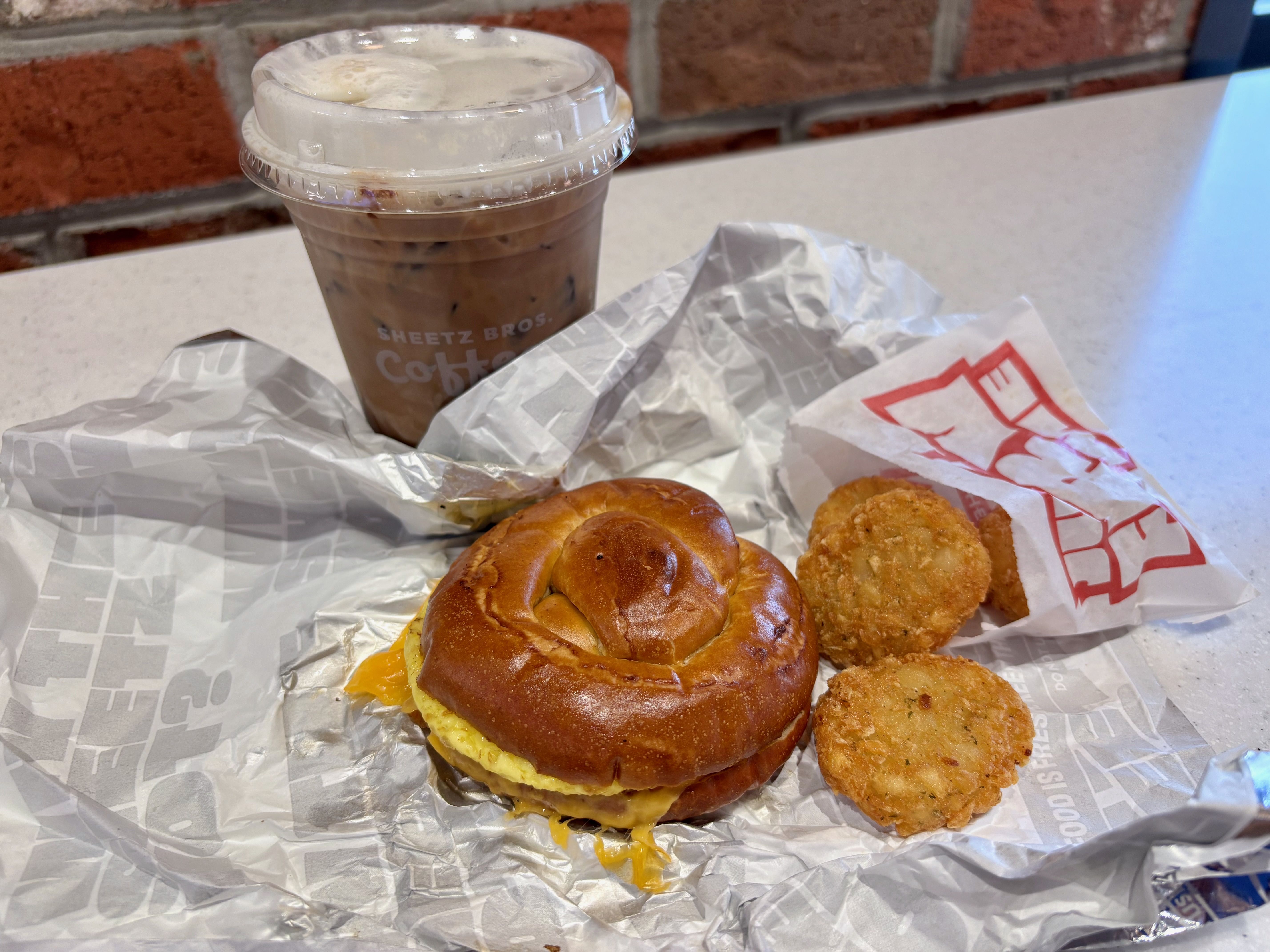An iced latte, breakfast sandwich and mini hashbrowns