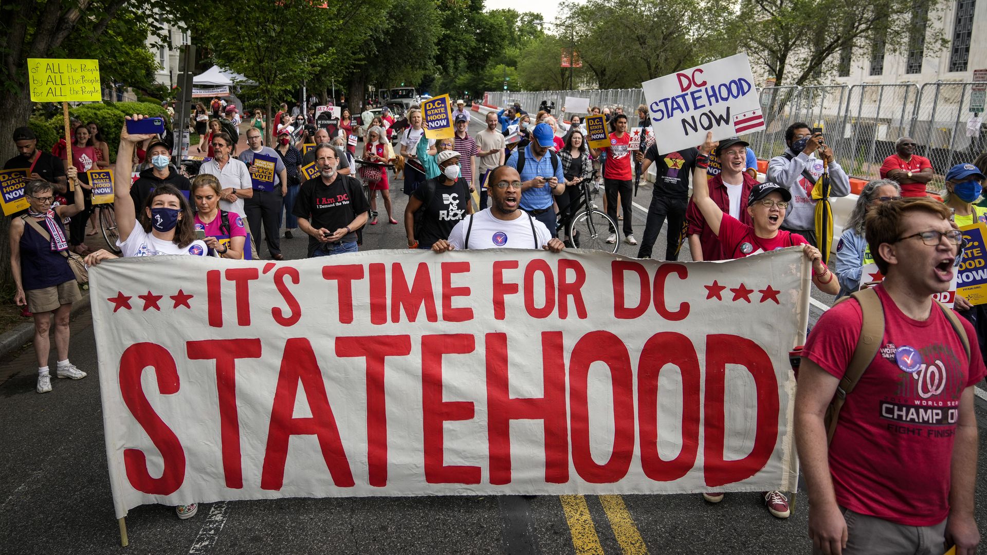 Supporters of D.C. statehood hold a large banner while marching down a street