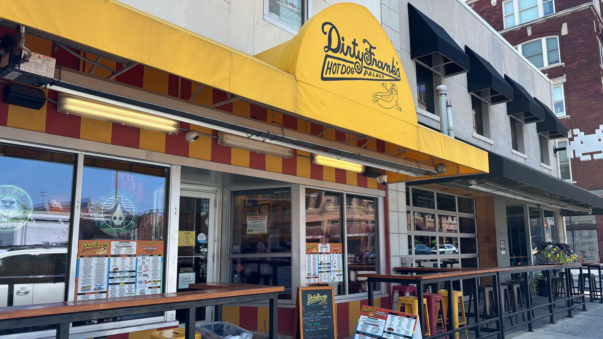 The front entrance to Dirty Frank's Hot Dog Palace, with a yellow awning