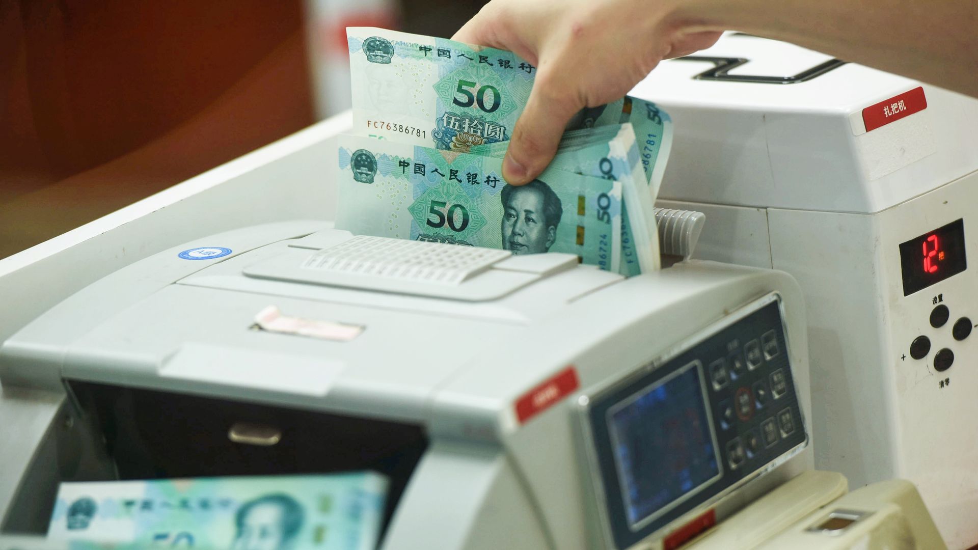 Chinese Yuan going through a counting machine at a bank